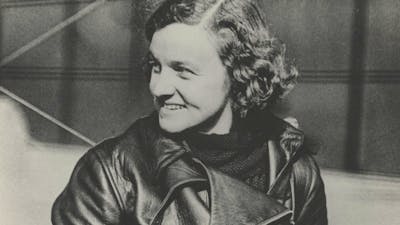 A sepia photograph of a woman with curly hair in flight gear.