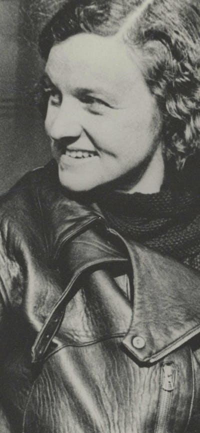 A sepia photograph of a woman with curly hair in flight gear.