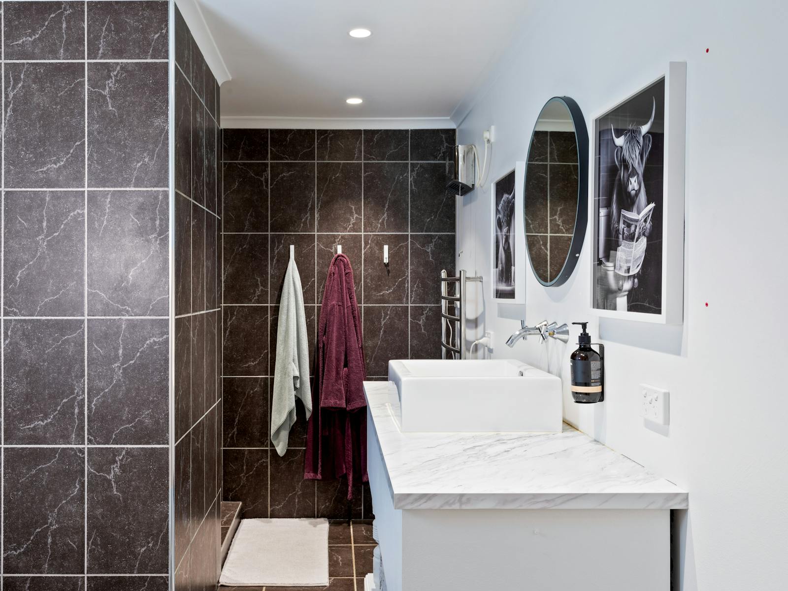 Bathroom with tiled walls showing vanity, mirror, towel and bathrobe