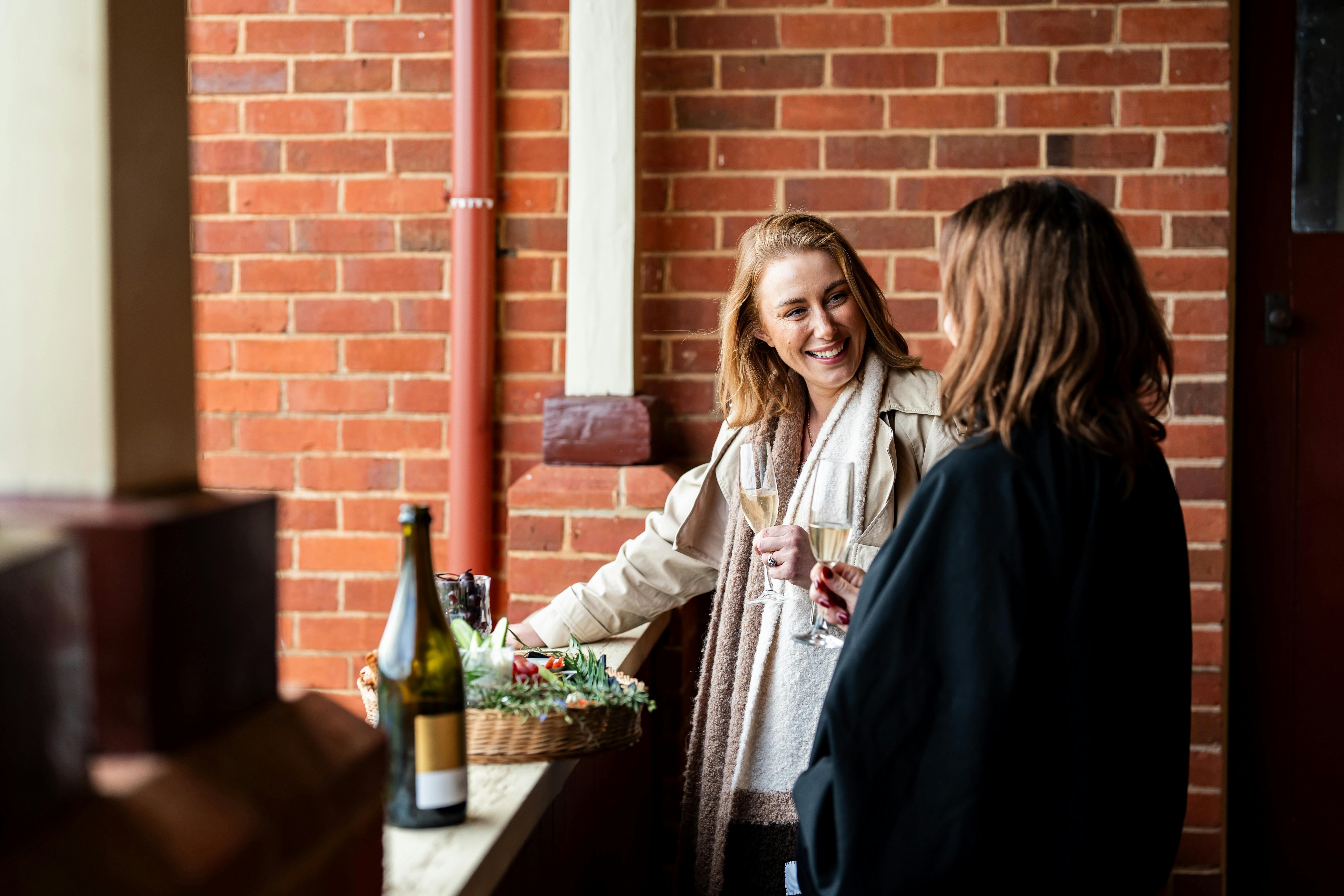 Two women standing on balcony with wine