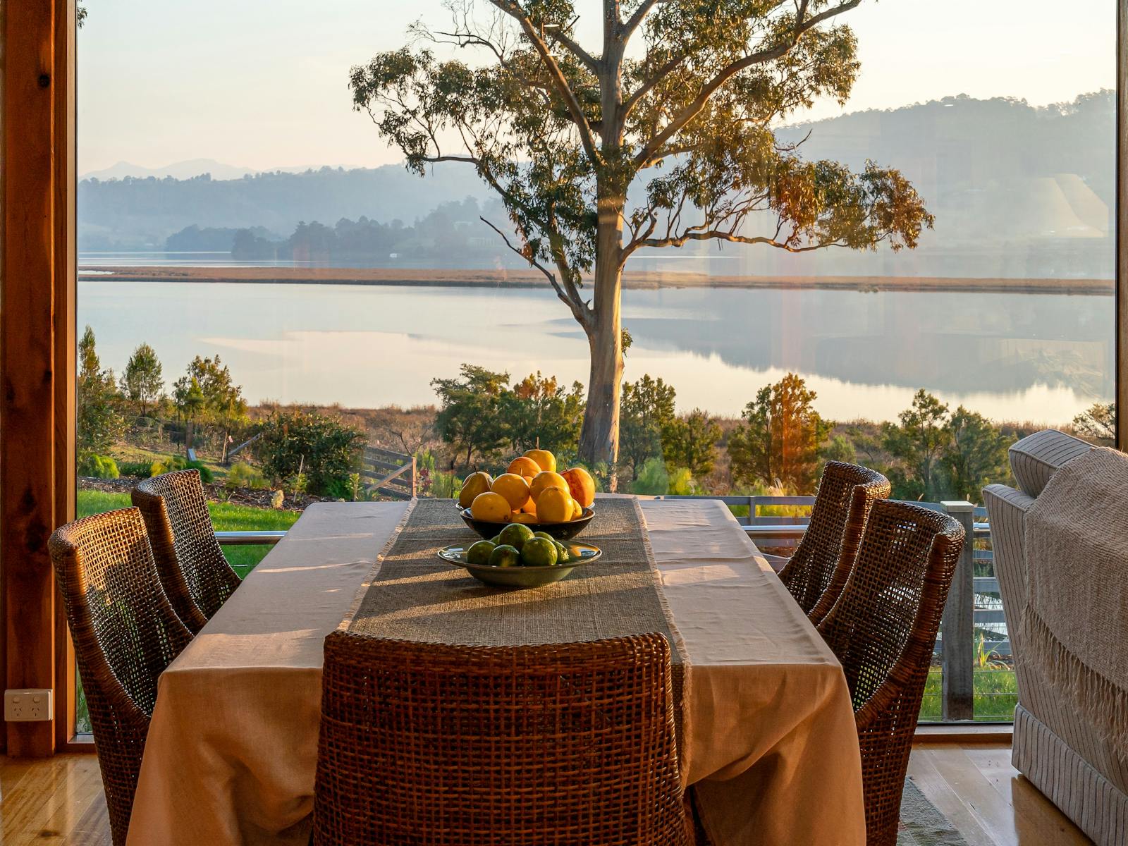 A photo of the Huon River Hideaway dining setting looking out the open windows across the Huon River
