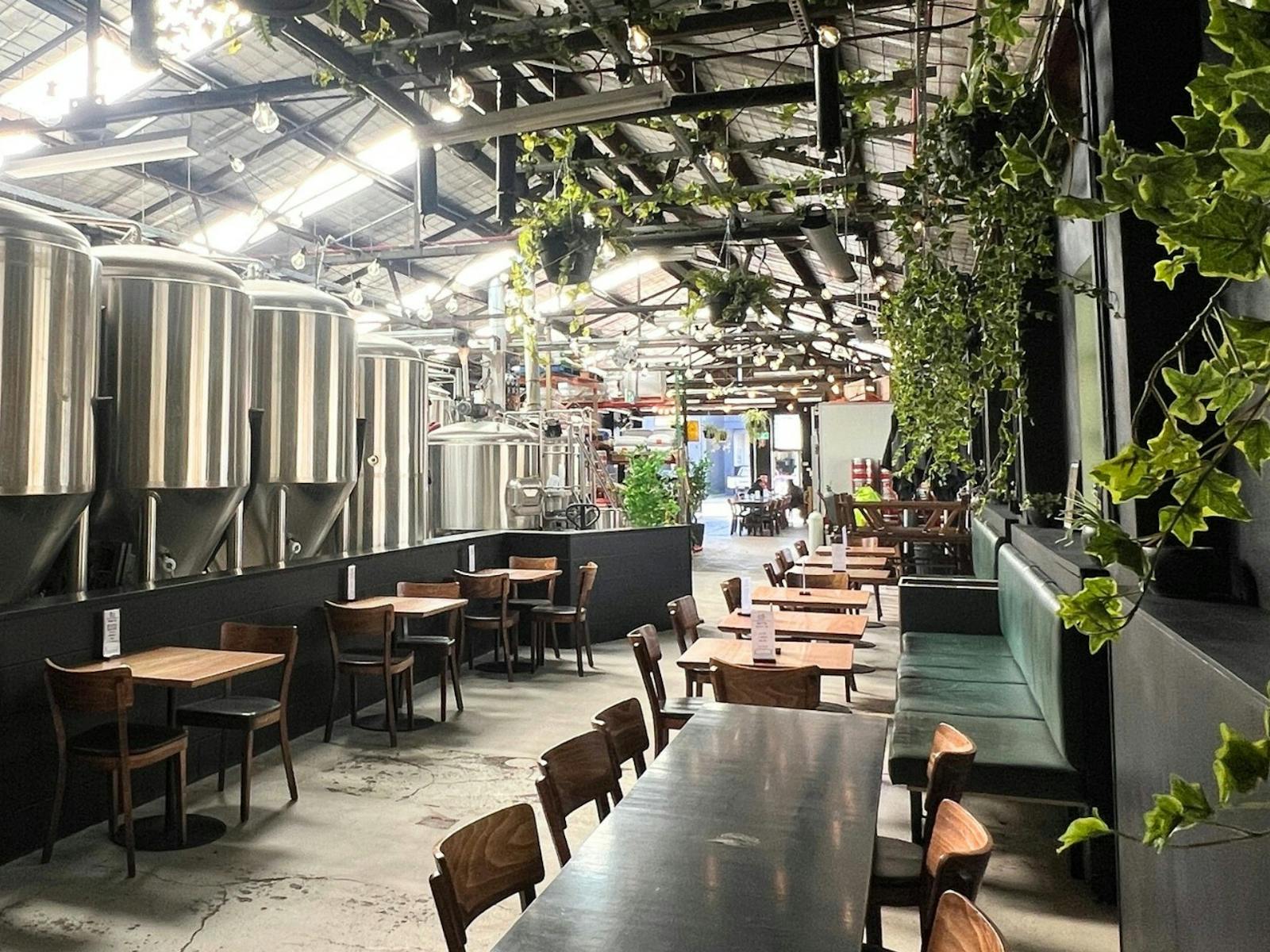 The back section of Batch's venue showing tables and large brew tanks