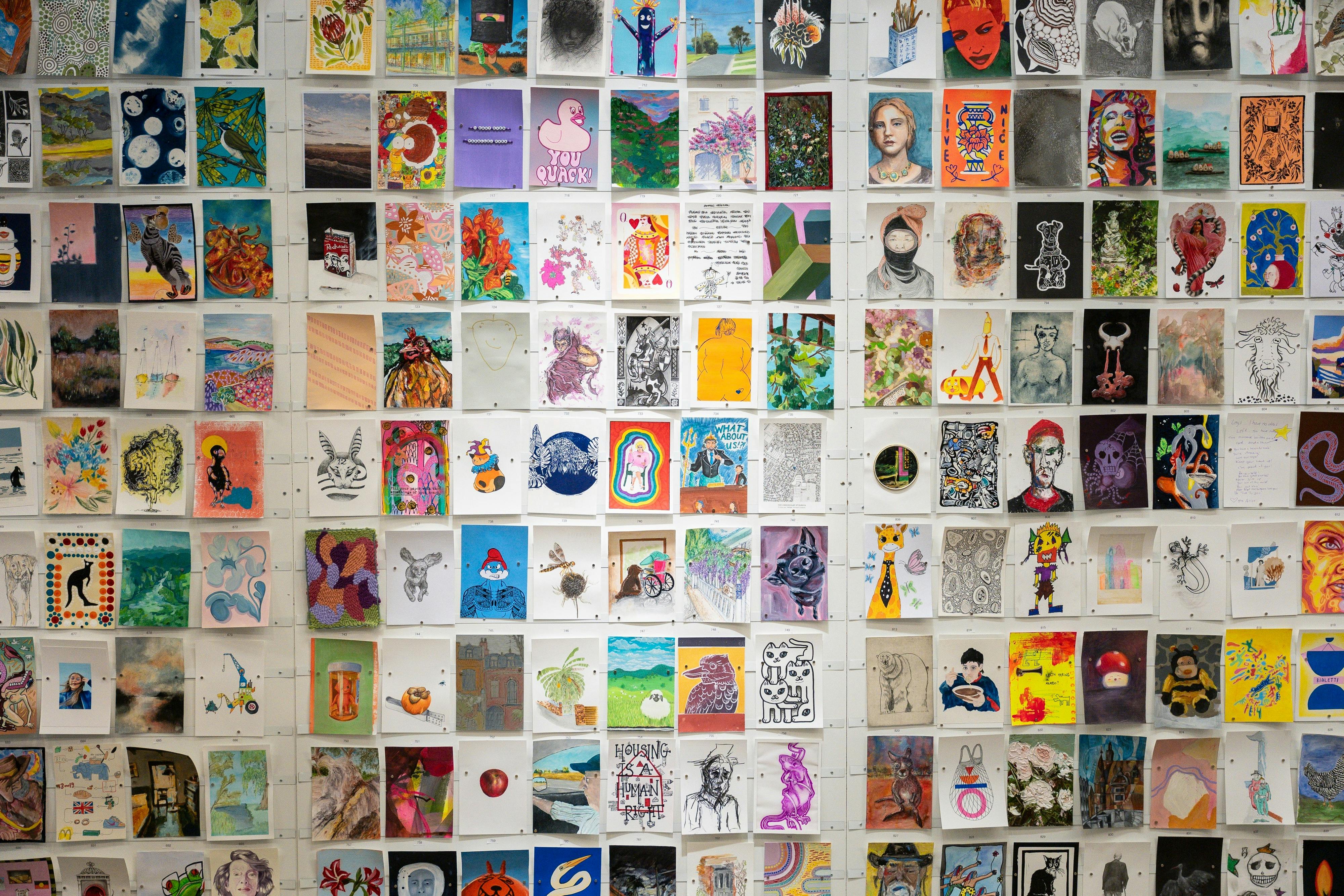 A5 artworks in portrait orientation displayed on a white wall at the Incognito Art Show.