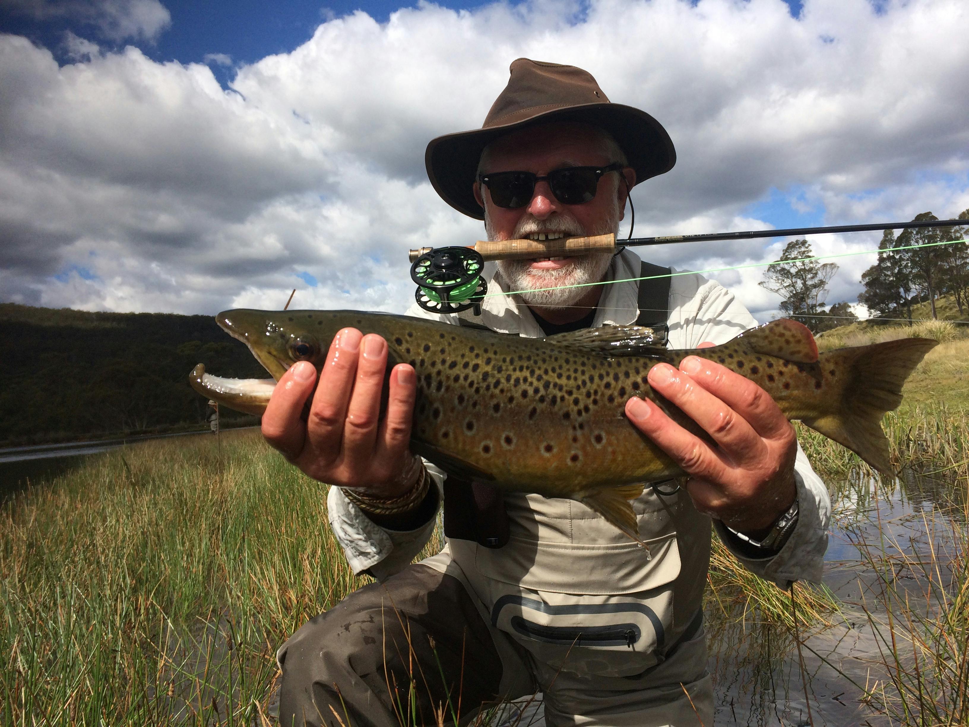 Tasmanian highland lake with still water and native bushland, fly fishing location.