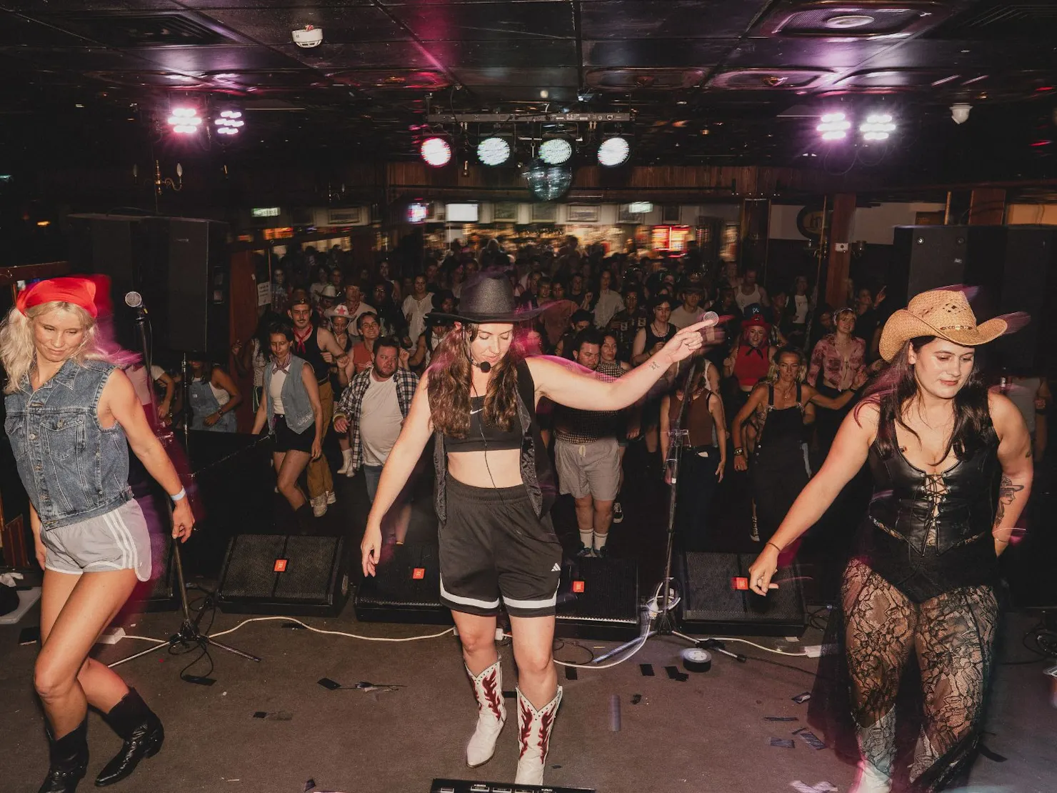 Saddle Club line dancers perform on stage before a large cheering crowd