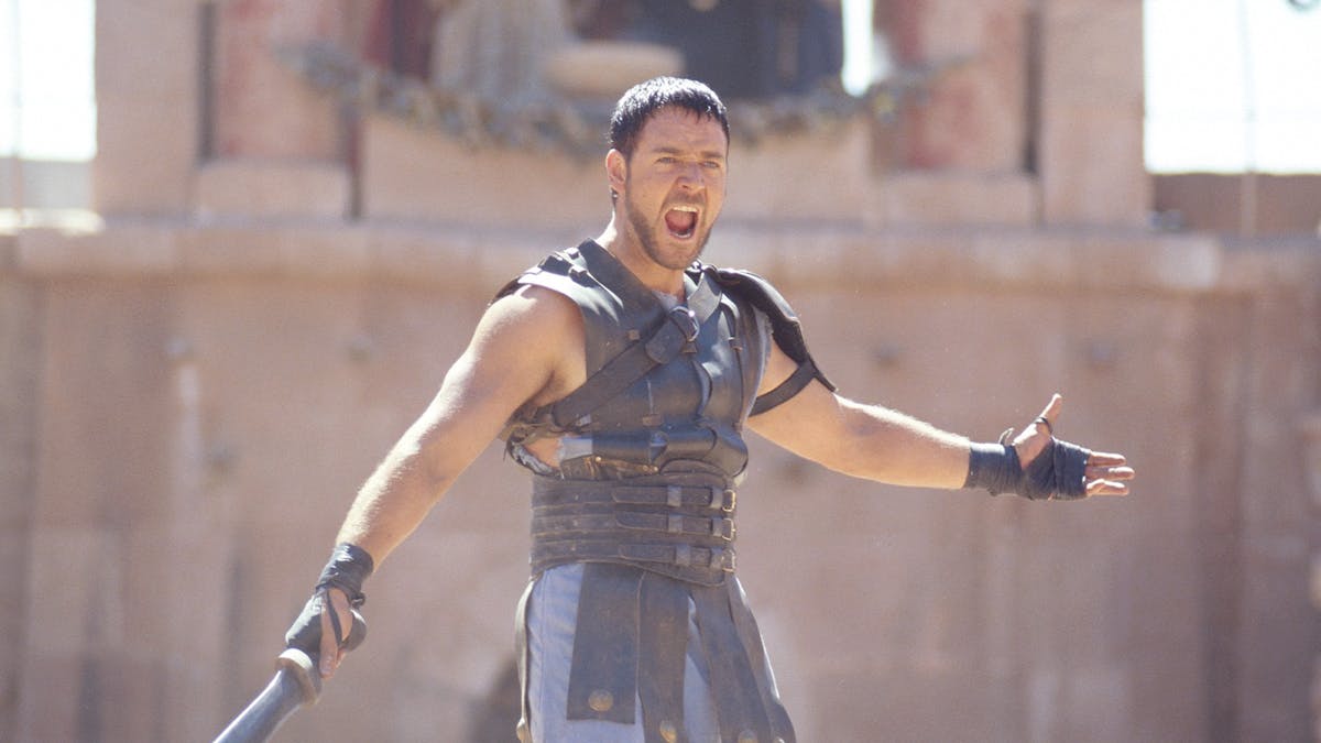 Russell Crowe's character in Gladiator holds a sword wearing medieval clothing preparing to fight