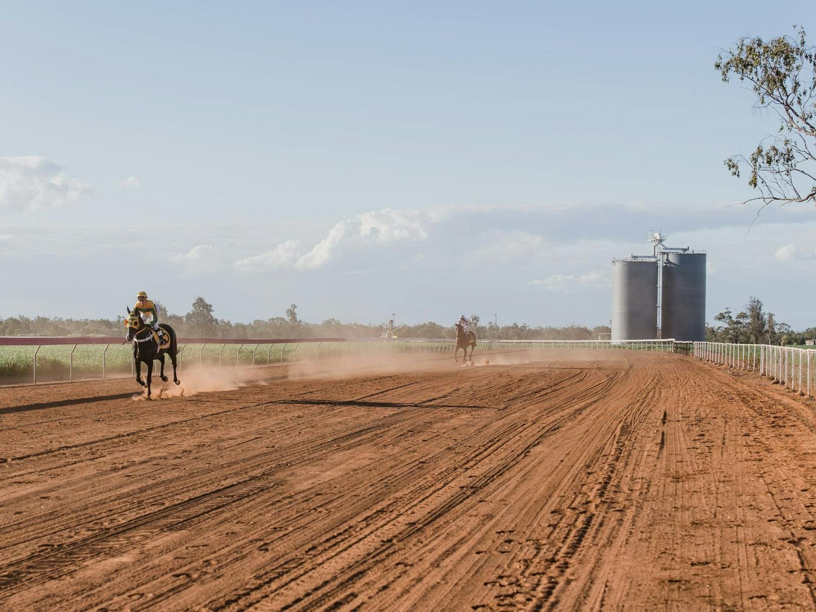 Red dirt racetrack with silos in the backgrond