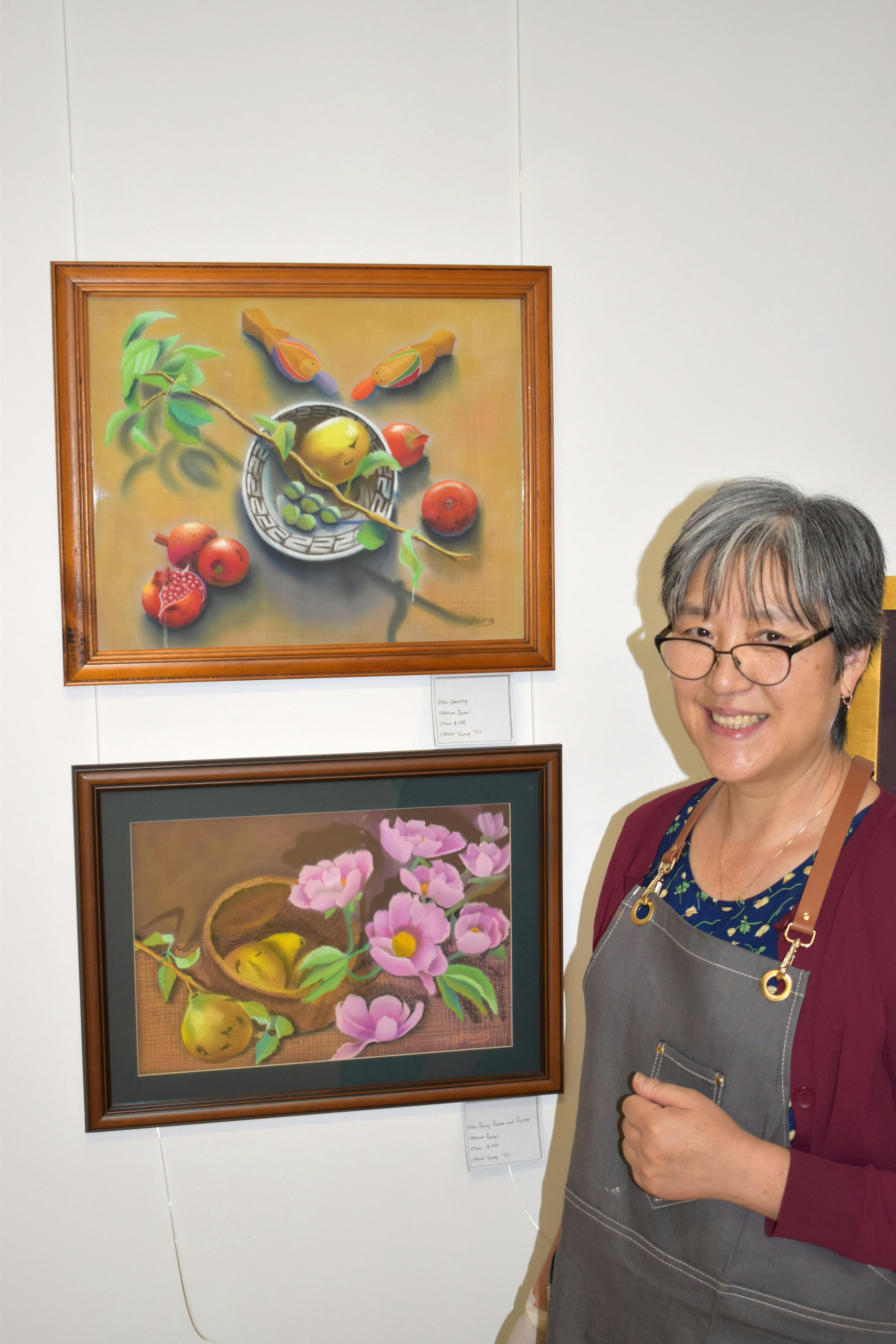 정물화를 그린 파스텔 작품 옆에서 미소 짓고 있는 예술가 영 틸.