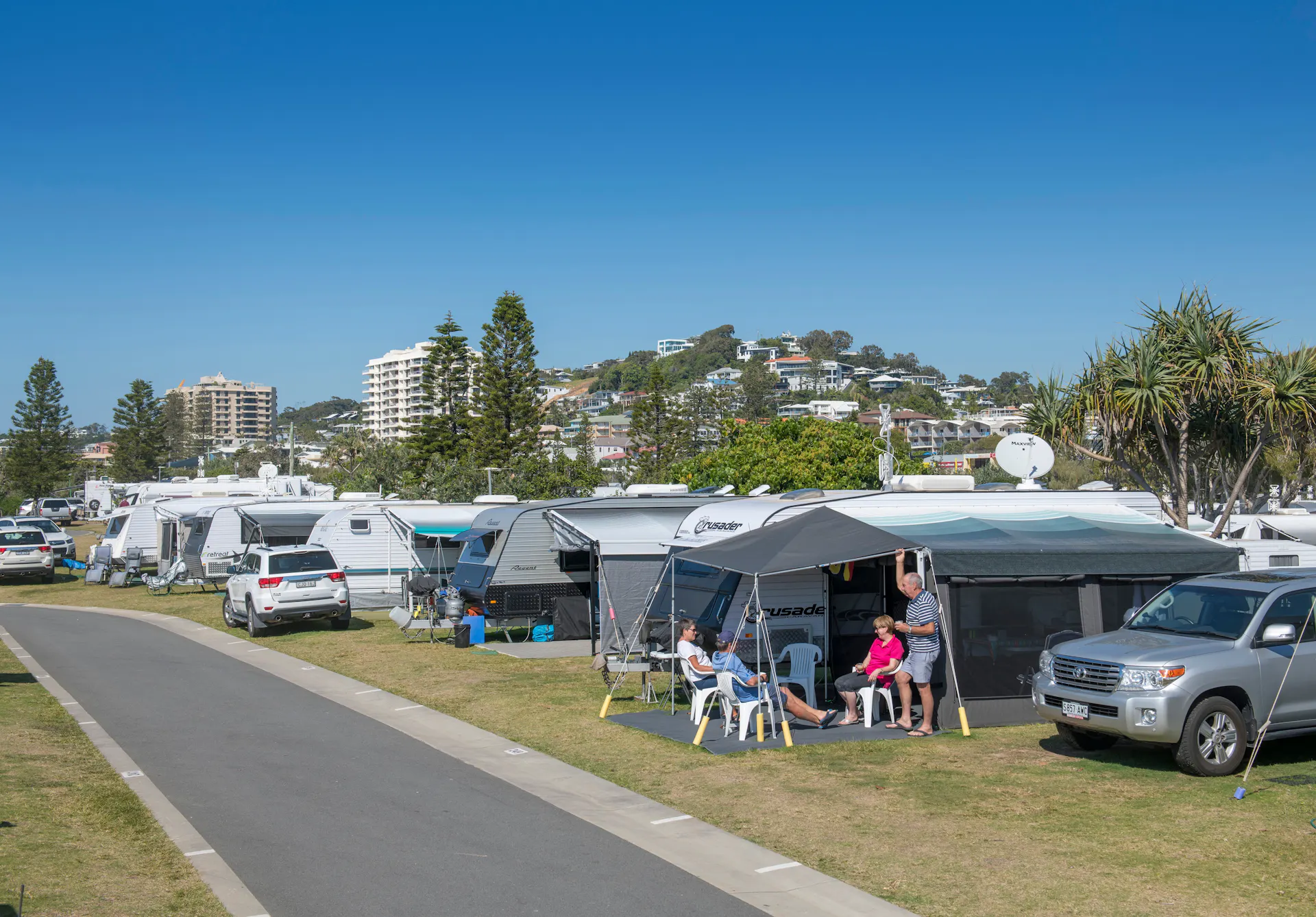 Image of a Coolum Beach Caravan site with people sitting under their awning