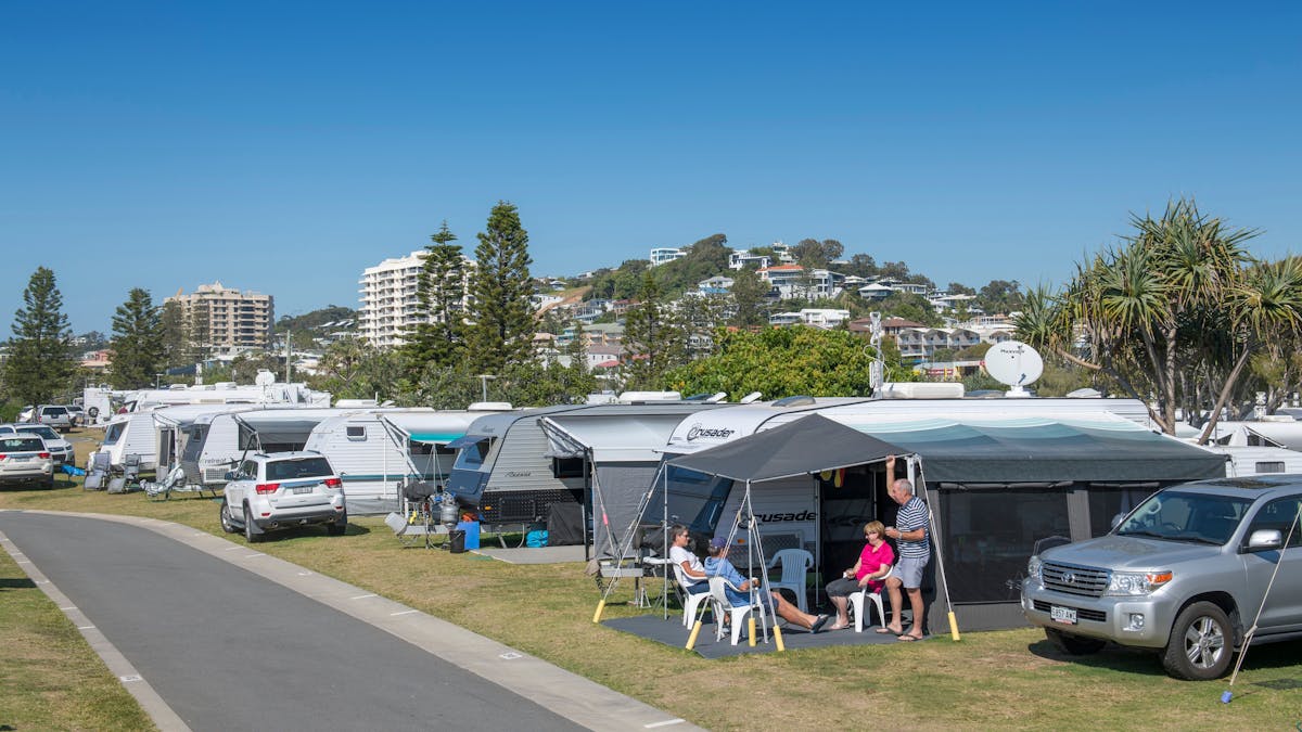 Image of a Coolum Beach Caravan site with people sitting under their awning