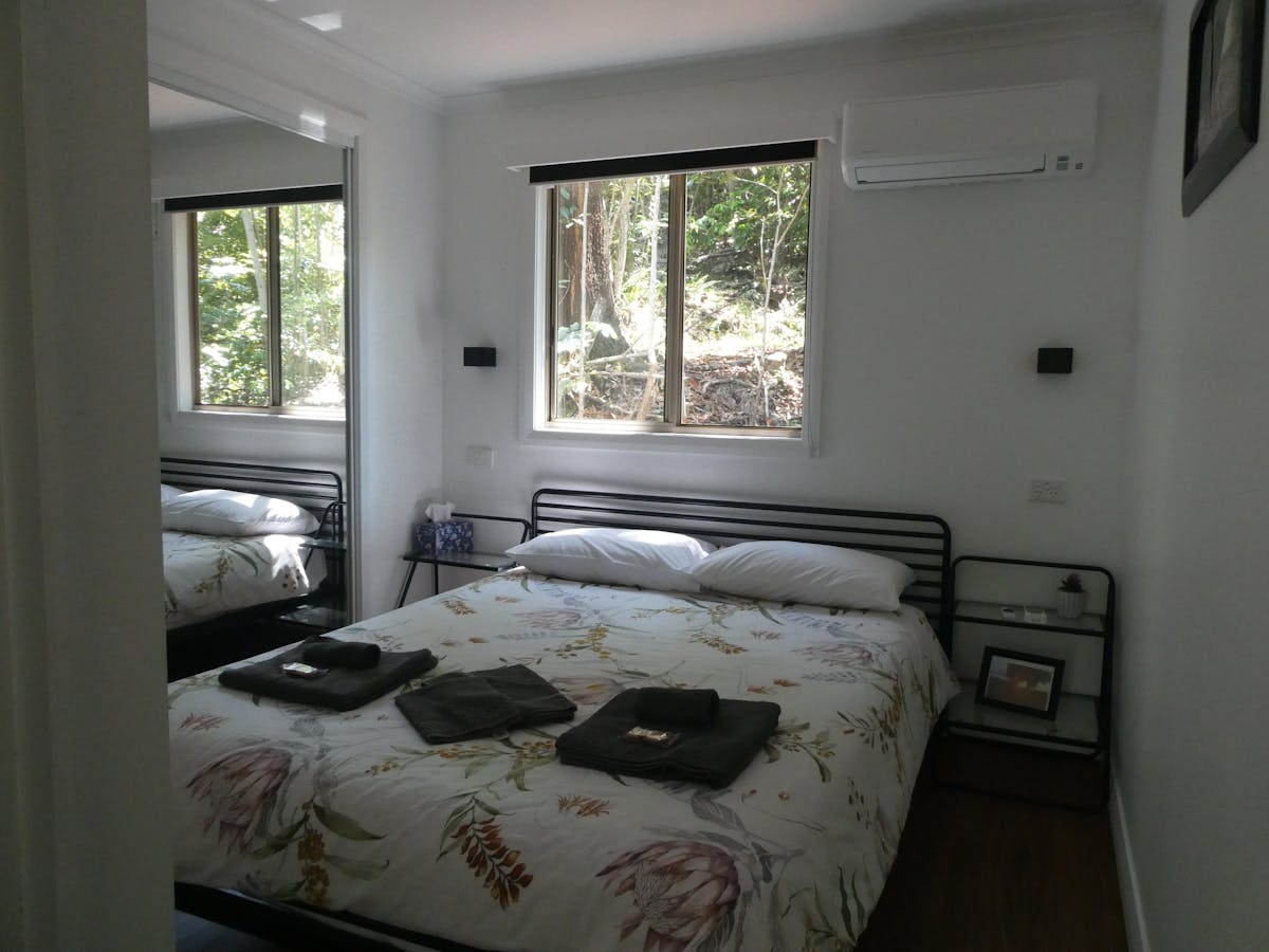Queen bedroom of the rainforest cabins, with a mirrored wardrobe