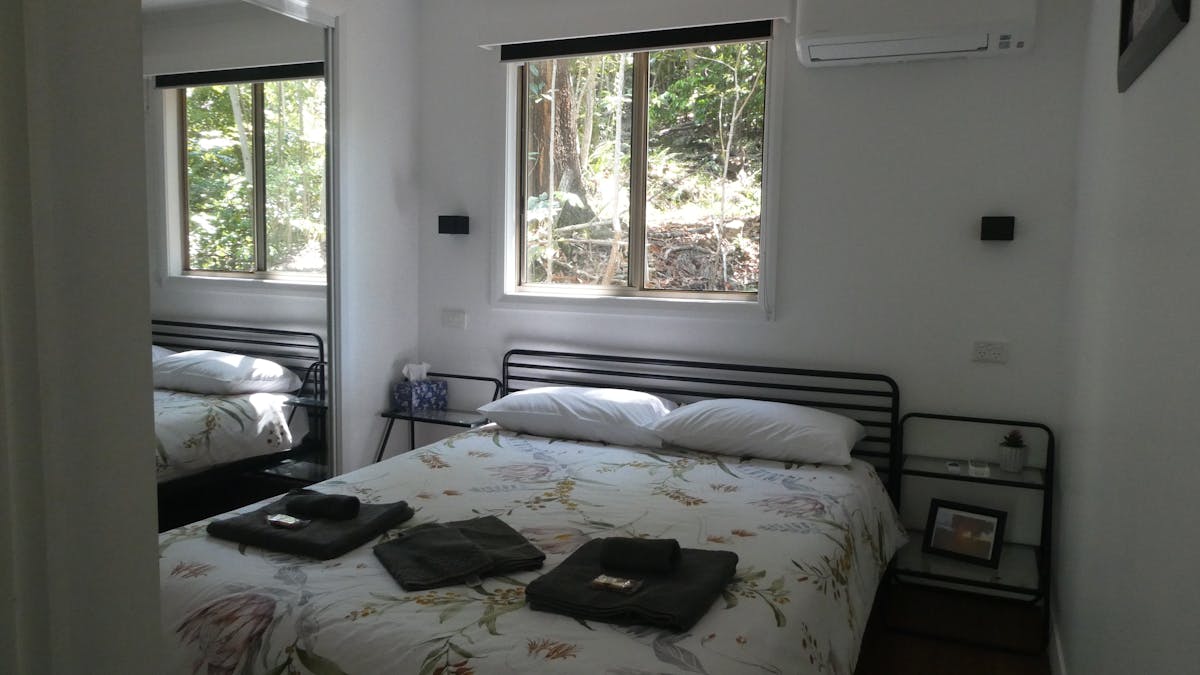 Queen bedroom of the rainforest cabins, with a mirrored wardrobe