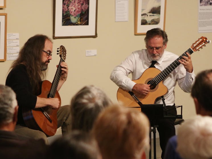 Two guitarists playing in art gallery