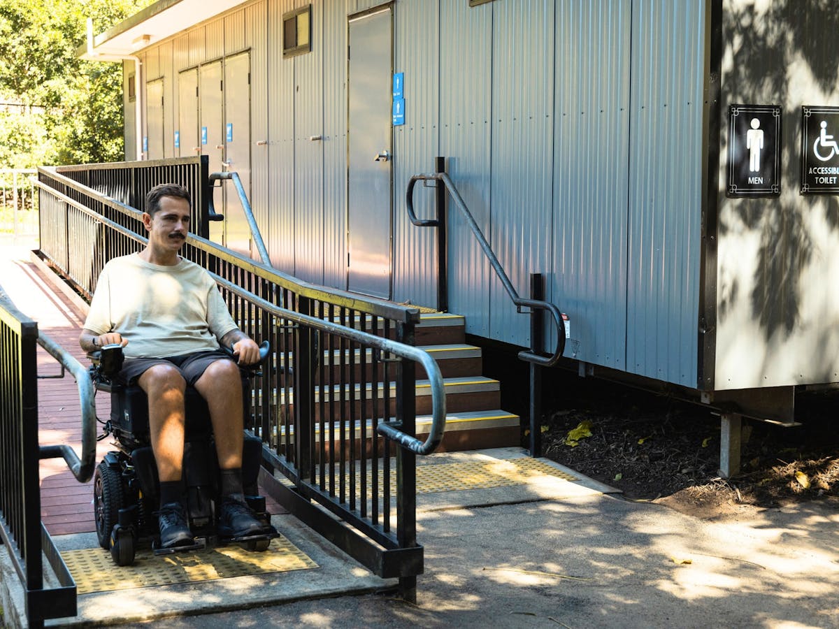 A visitor using the wheelchair ramp at an accessible toilet block at Lone Pine Koala Sanctuary.