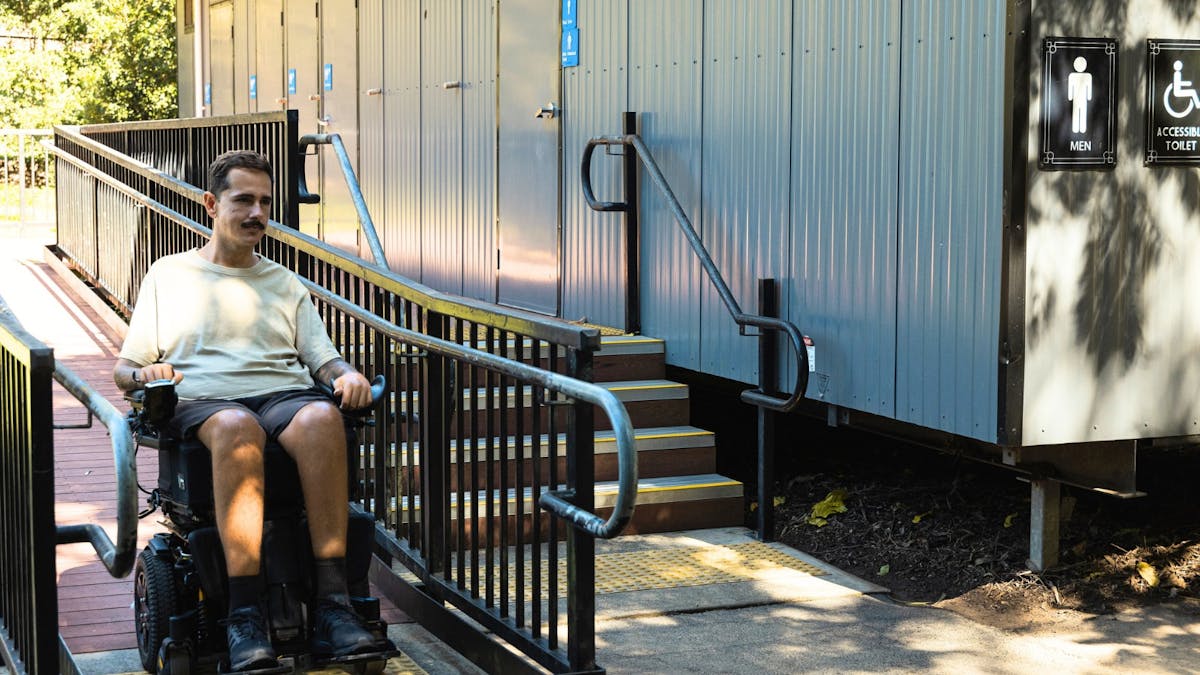 A visitor using the wheelchair ramp at an accessible toilet block at Lone Pine Koala Sanctuary.