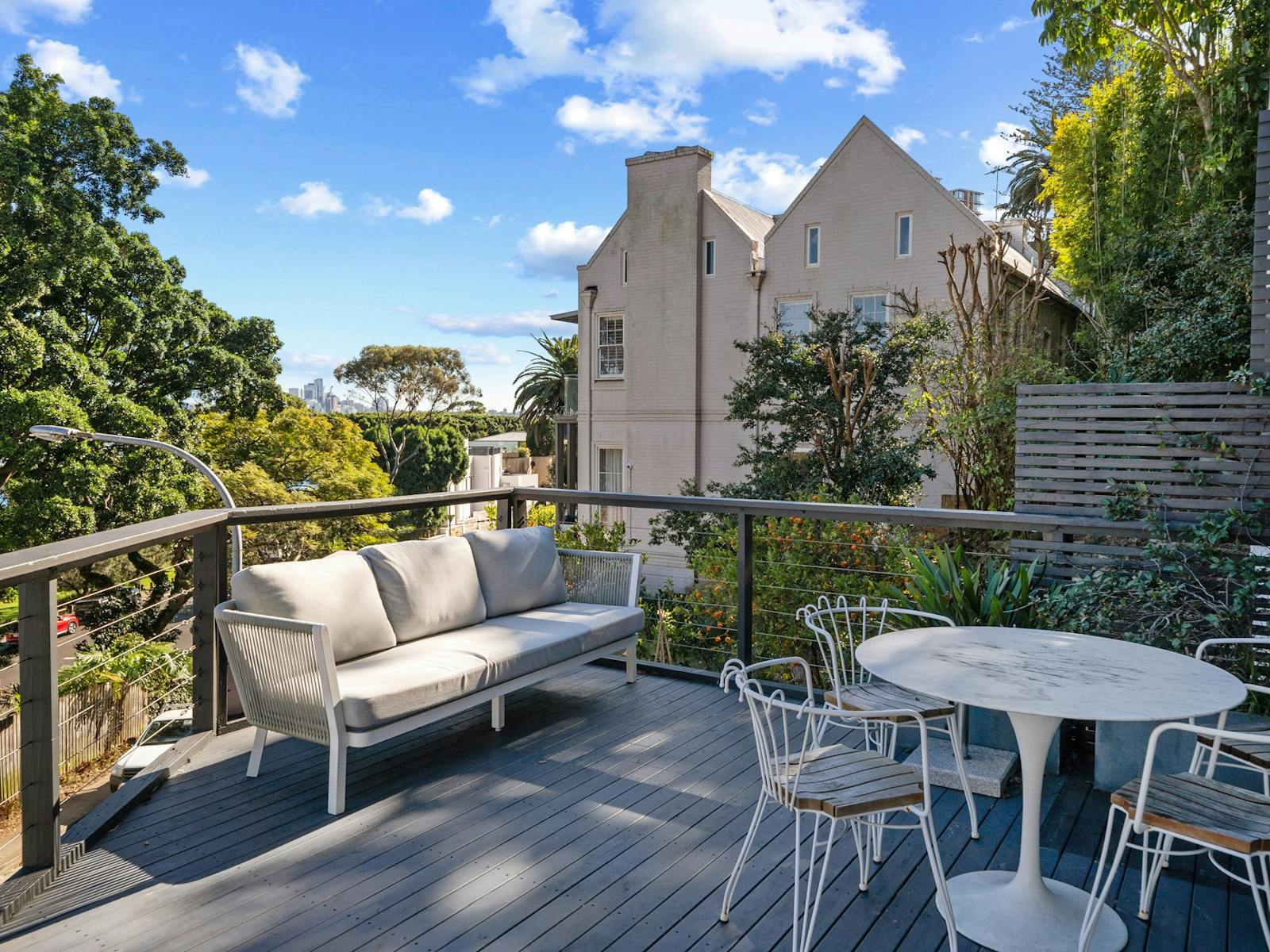 Outdoor deck with seating, city skyline views, and lush greenery.