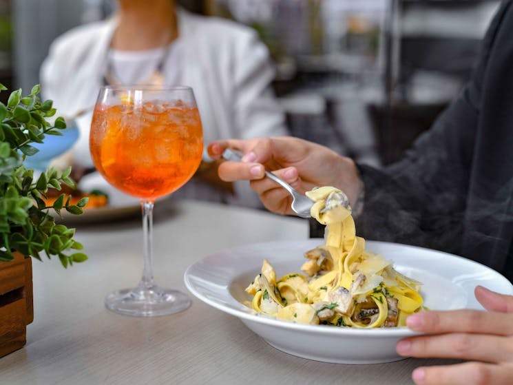Eastbank Cafe outdoor dining table with a creamy chicken and mushroom fetuccini and aperol spritz
