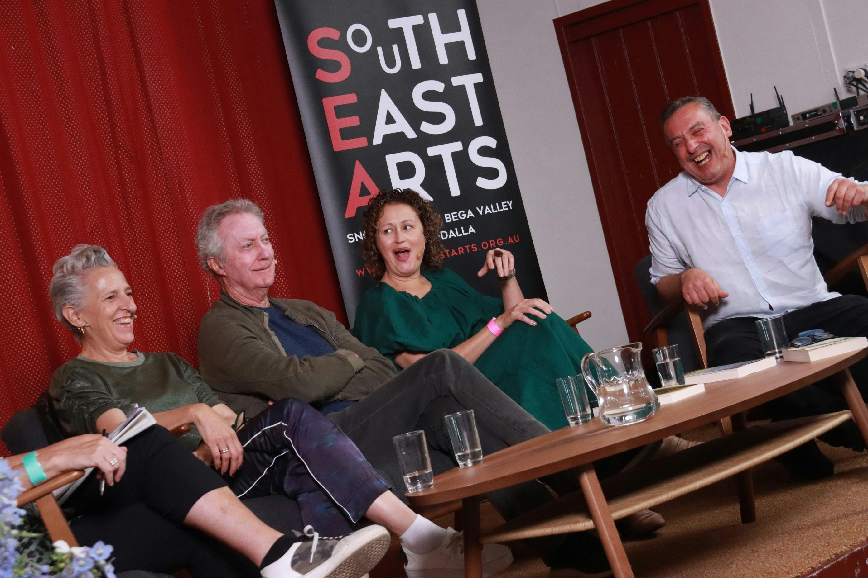 シャーロット・ウッド、ブライアン・ブラウン、ギャビー・ストラウド、クリストス・ツィオルカスを含む作家たちのパネリストたちが笑っている