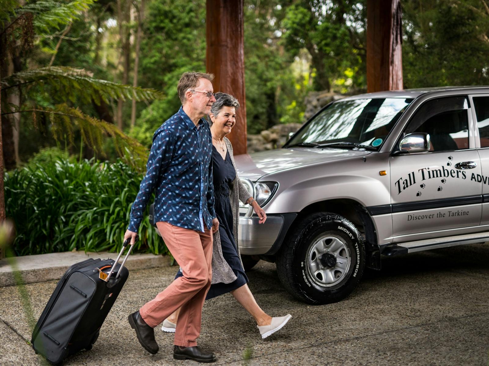 Couple arriving to Tall Timbers with luggage  with Adventure Tour 4WD in background