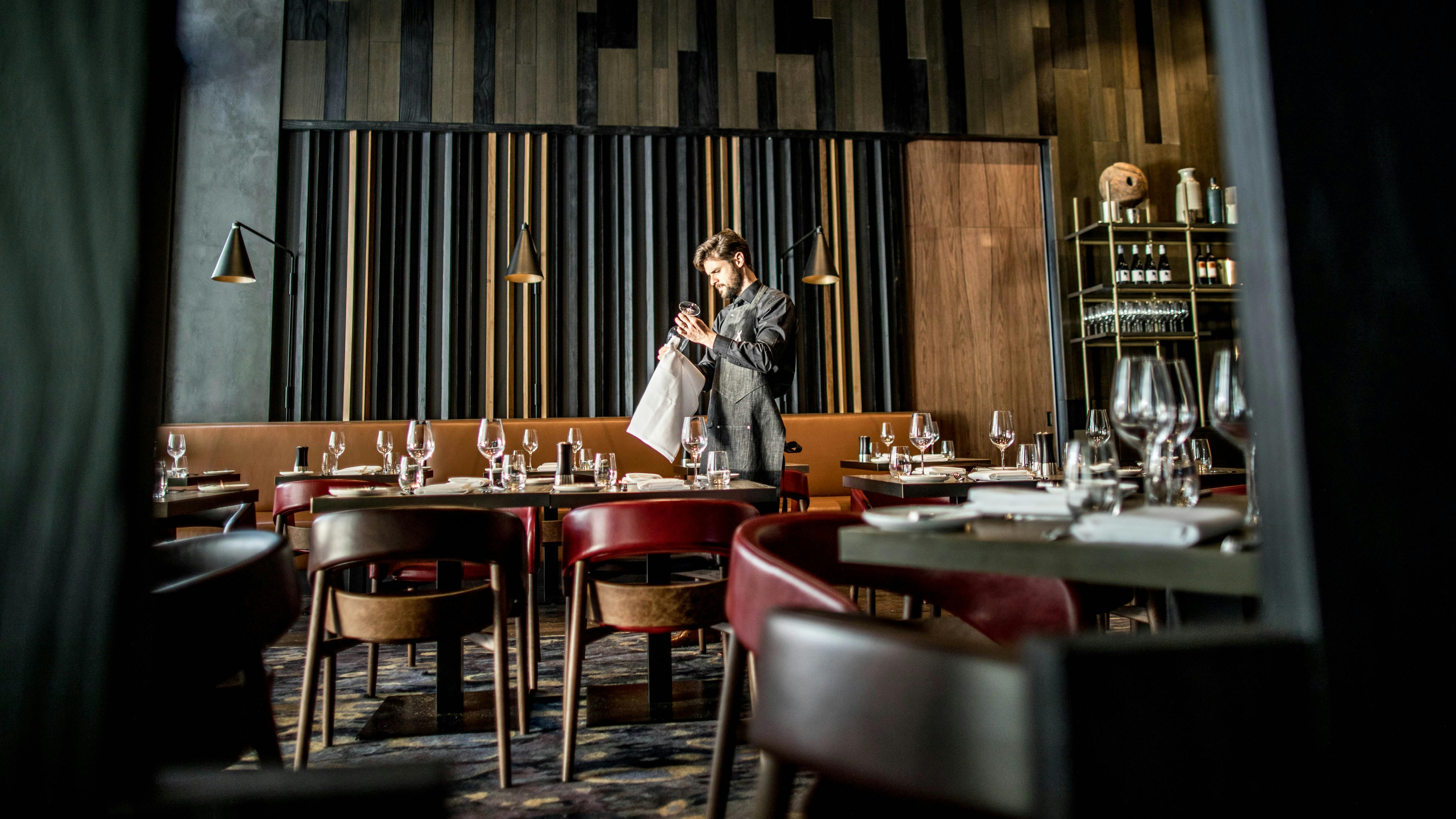 A server polishing a glass amongst dining tables