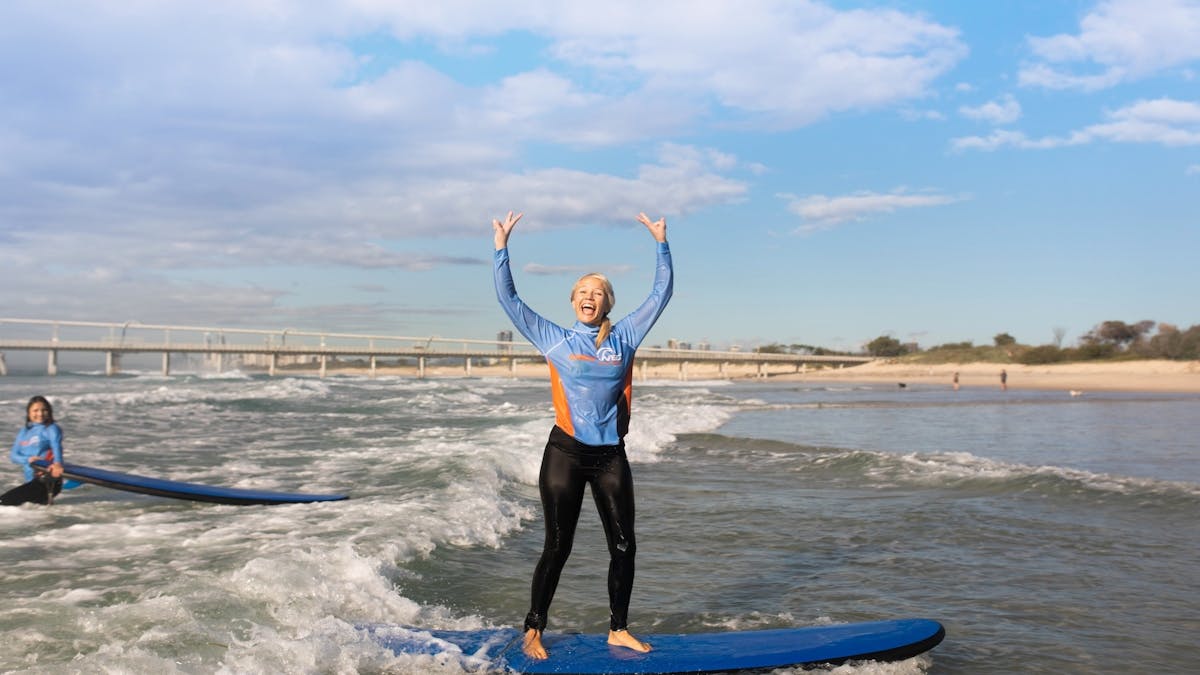 A stoked student standing up on her first wave!