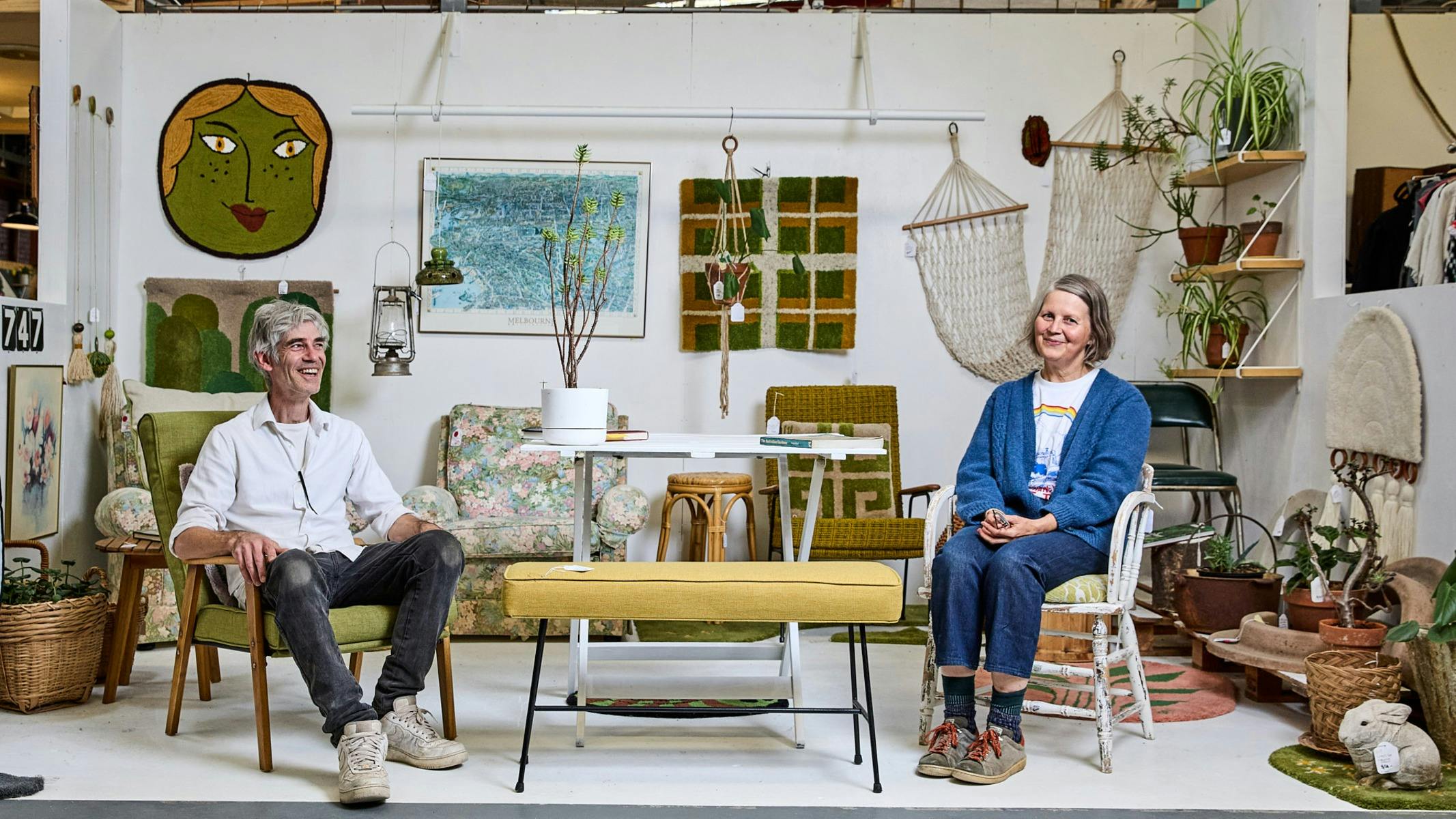 a woman and a man sitting in a furniture shop smiling