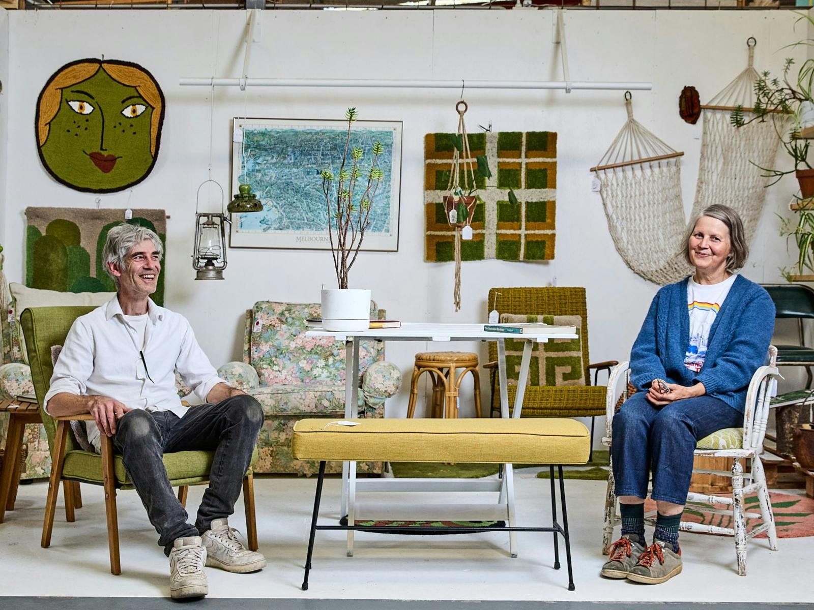 a woman and a man sitting in a furniture shop smiling