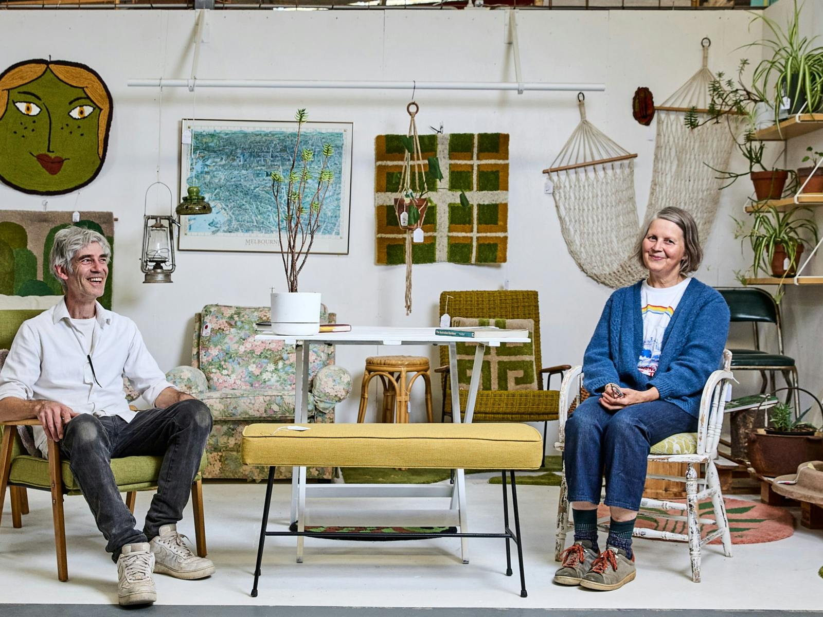 a woman and a man sitting in a furniture shop smiling