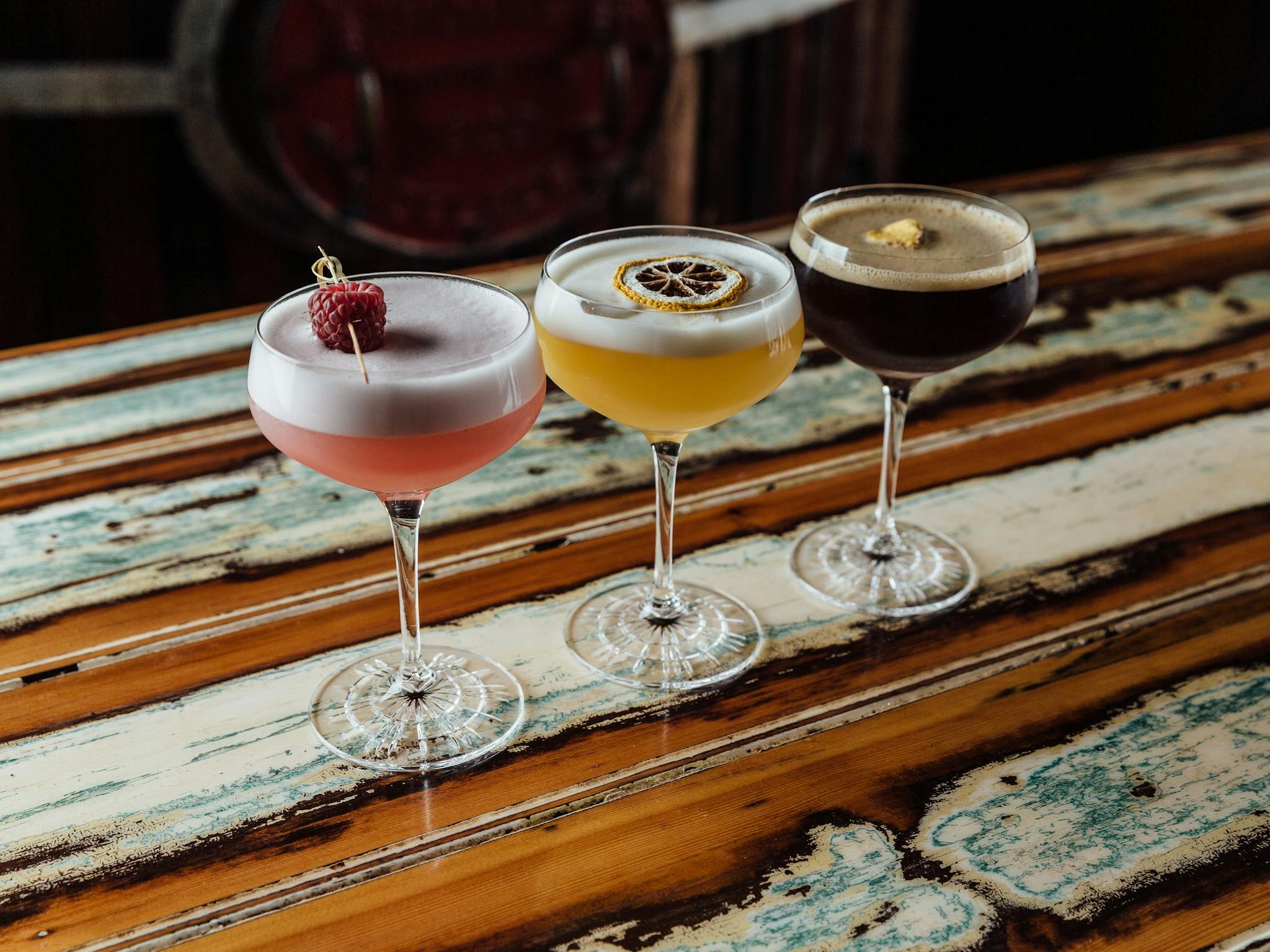 Three cocktails sitting on a wooden table.