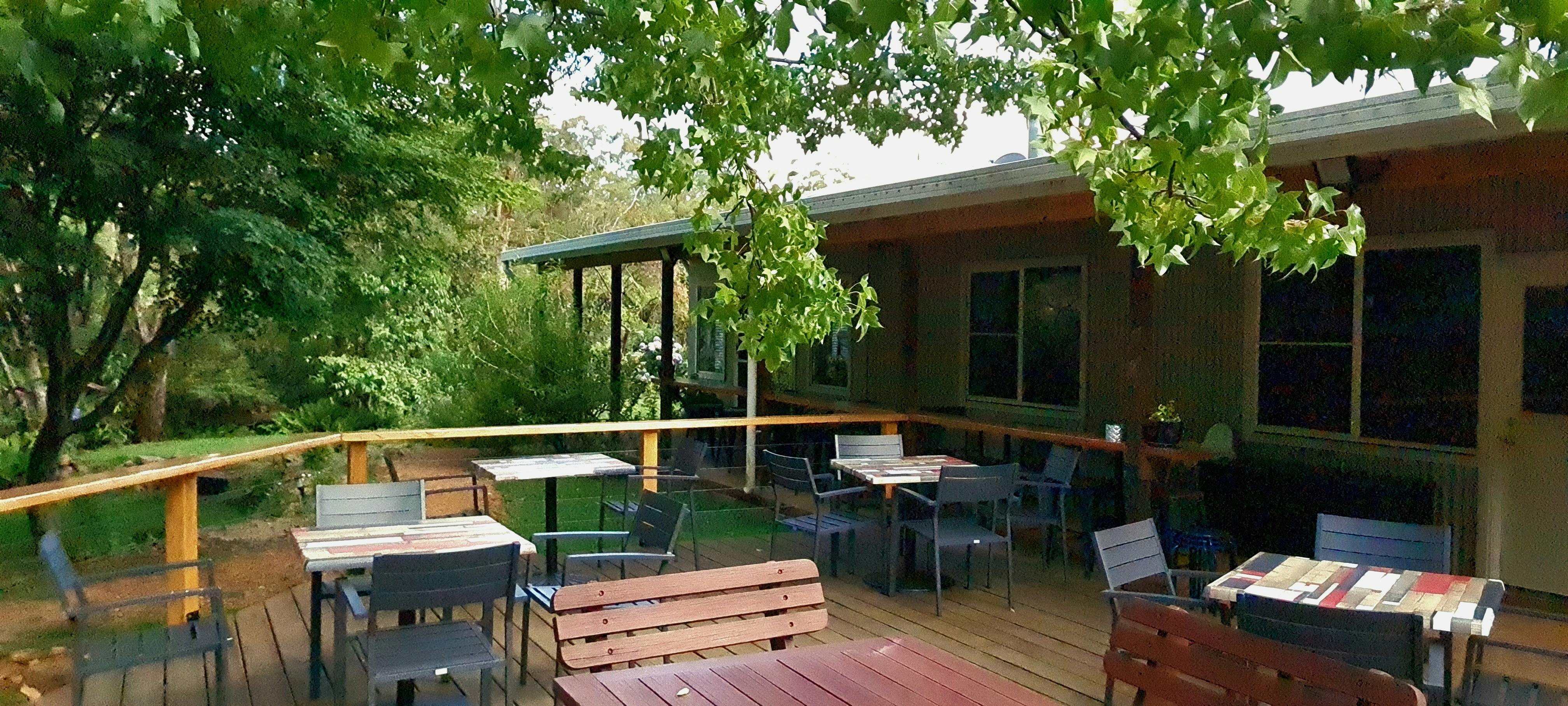timber deck under cool trees for outdoor dining at The Drunken Trout Cafe