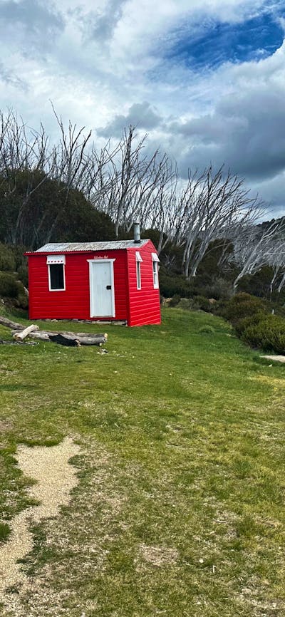A red hut in the centre of the landscape with a mountain to the right.