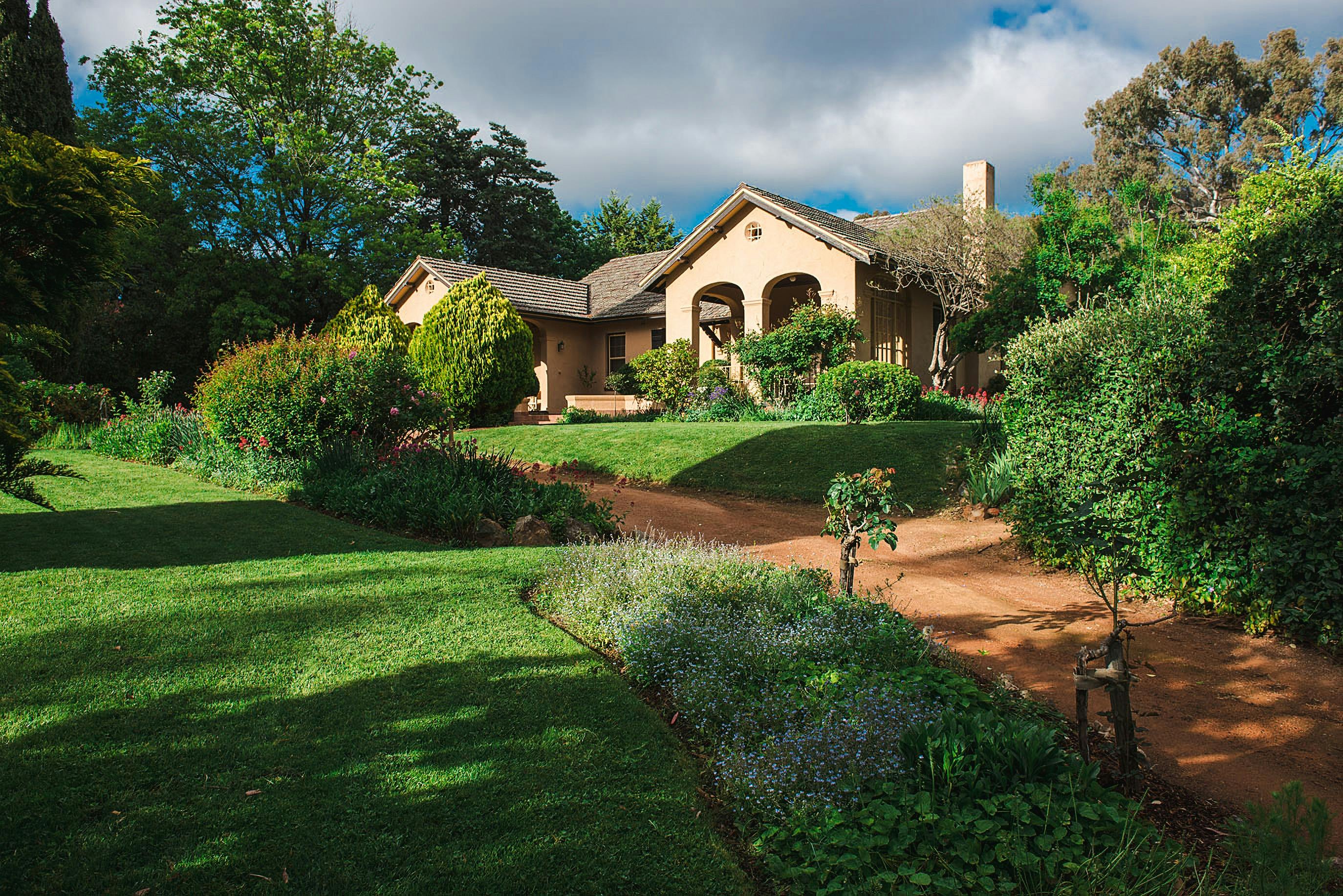 A view of Calthorpes House from the driveway, featuring plants in the foreground and house in back