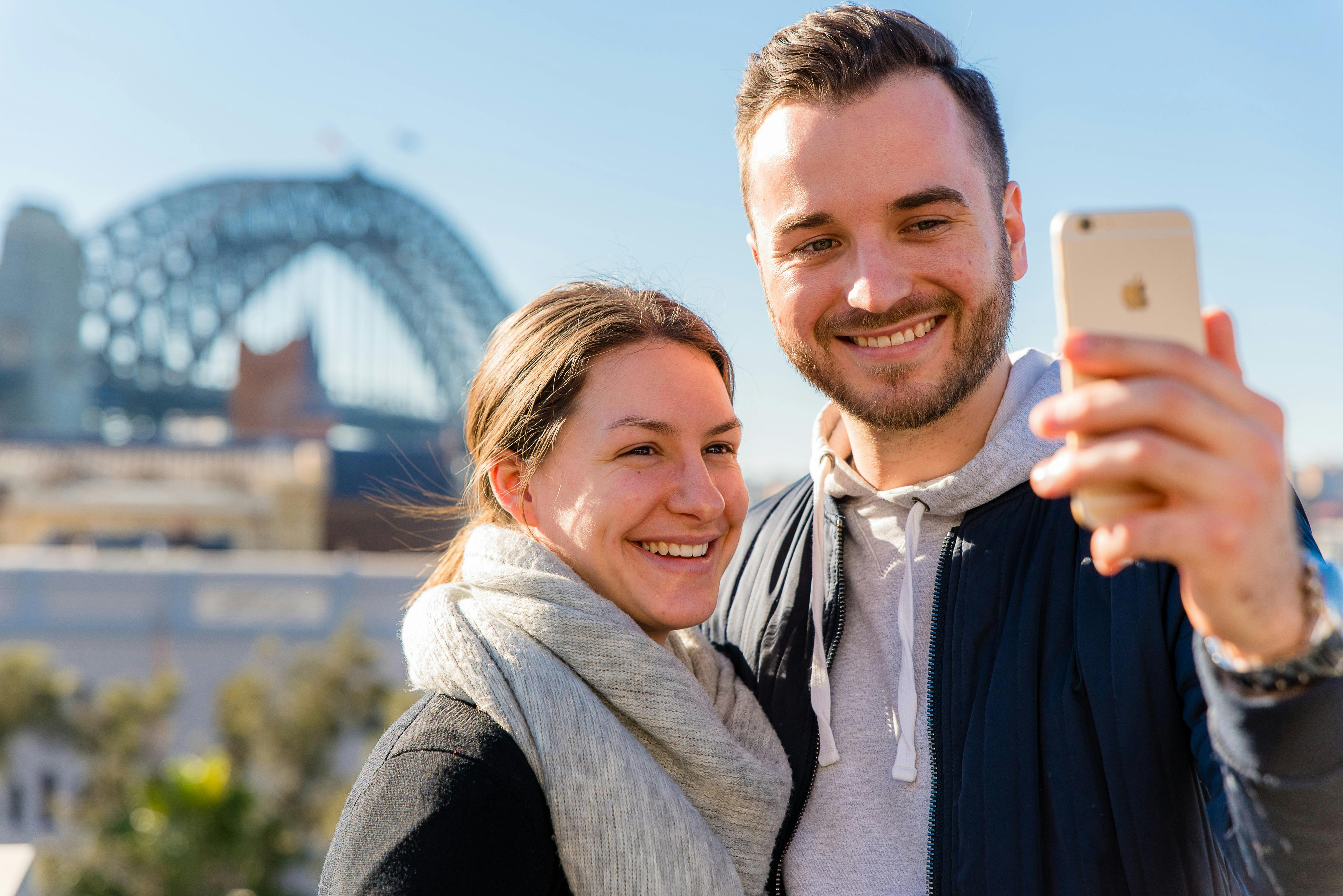 Smartphone selfie young couple with Harbour Bridge backdrop