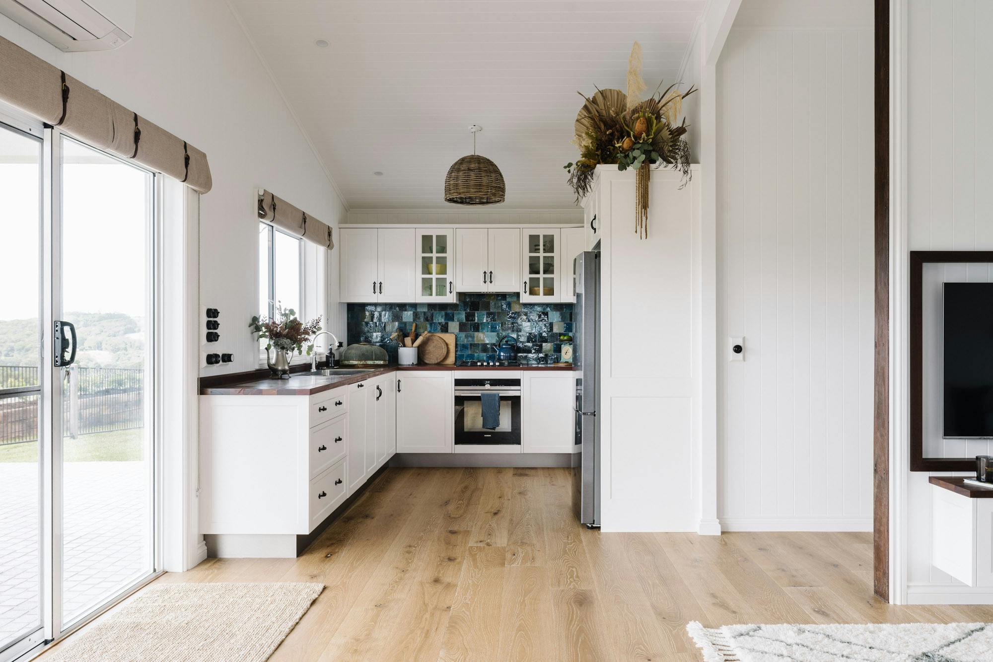 Kitchen with handcrafted reclaimed timber benchtops and Jatana tiles splashback cane pendant light