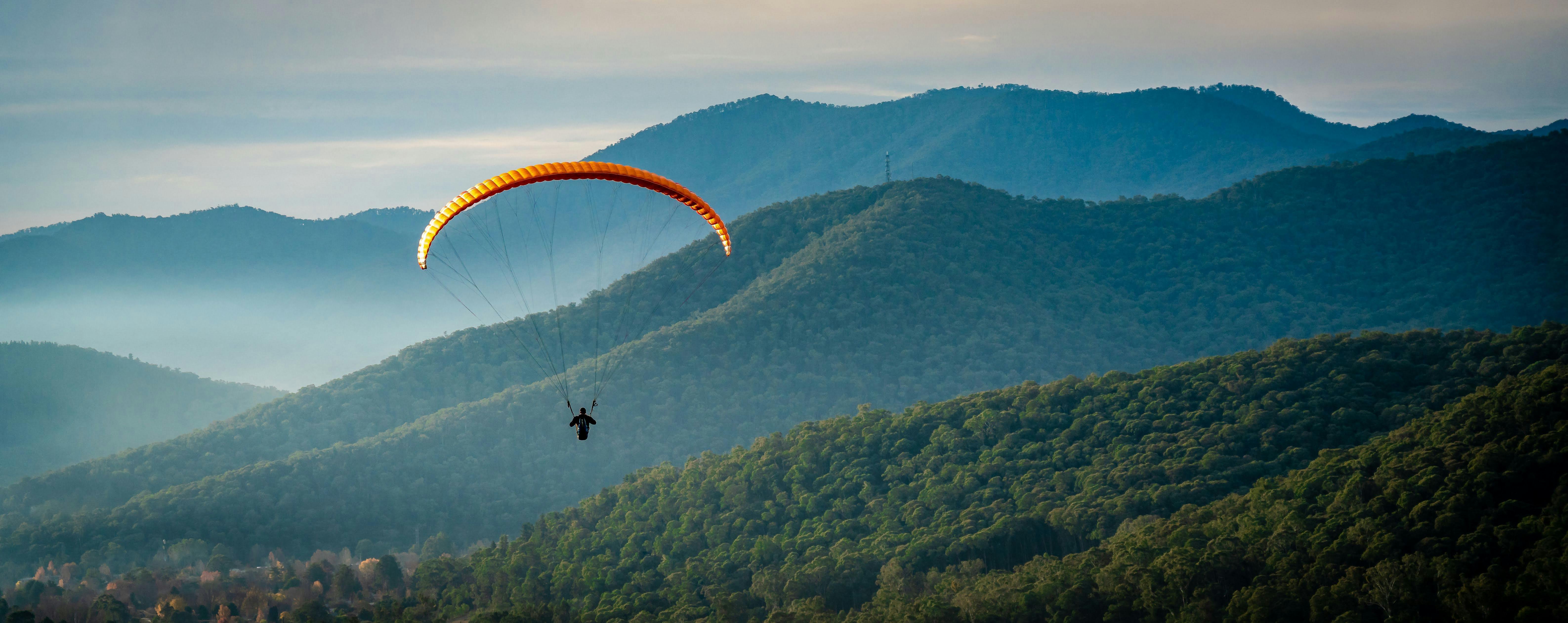 A paraglider flies over Bright Mountains