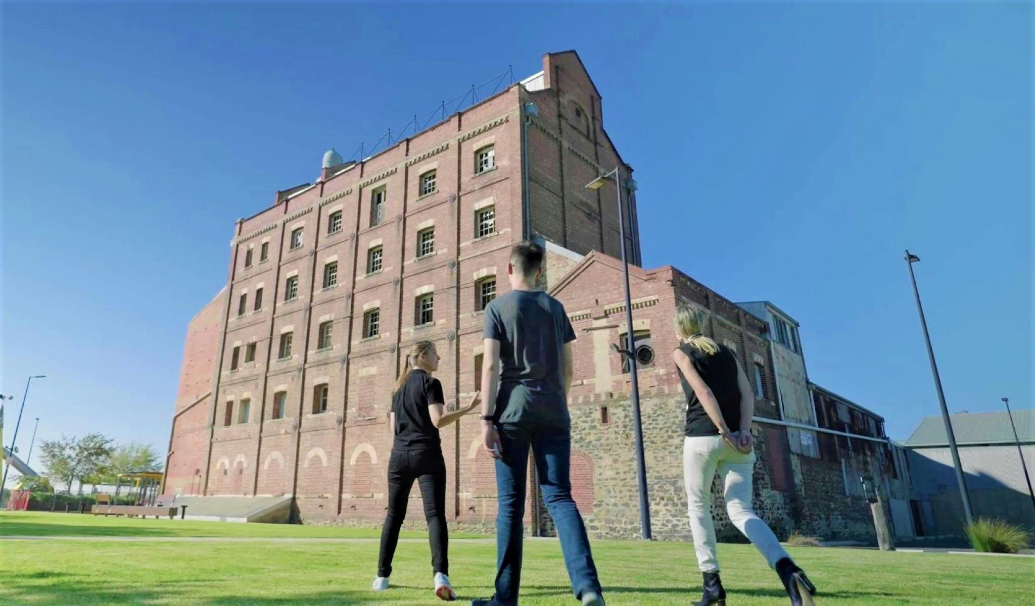 A guide tells guests on the Port Adelaide Walking Tour about the Hart's Mill building.