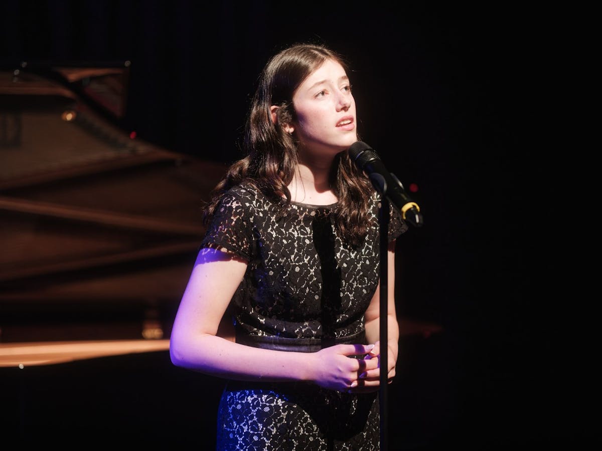 A young girl sings on stage