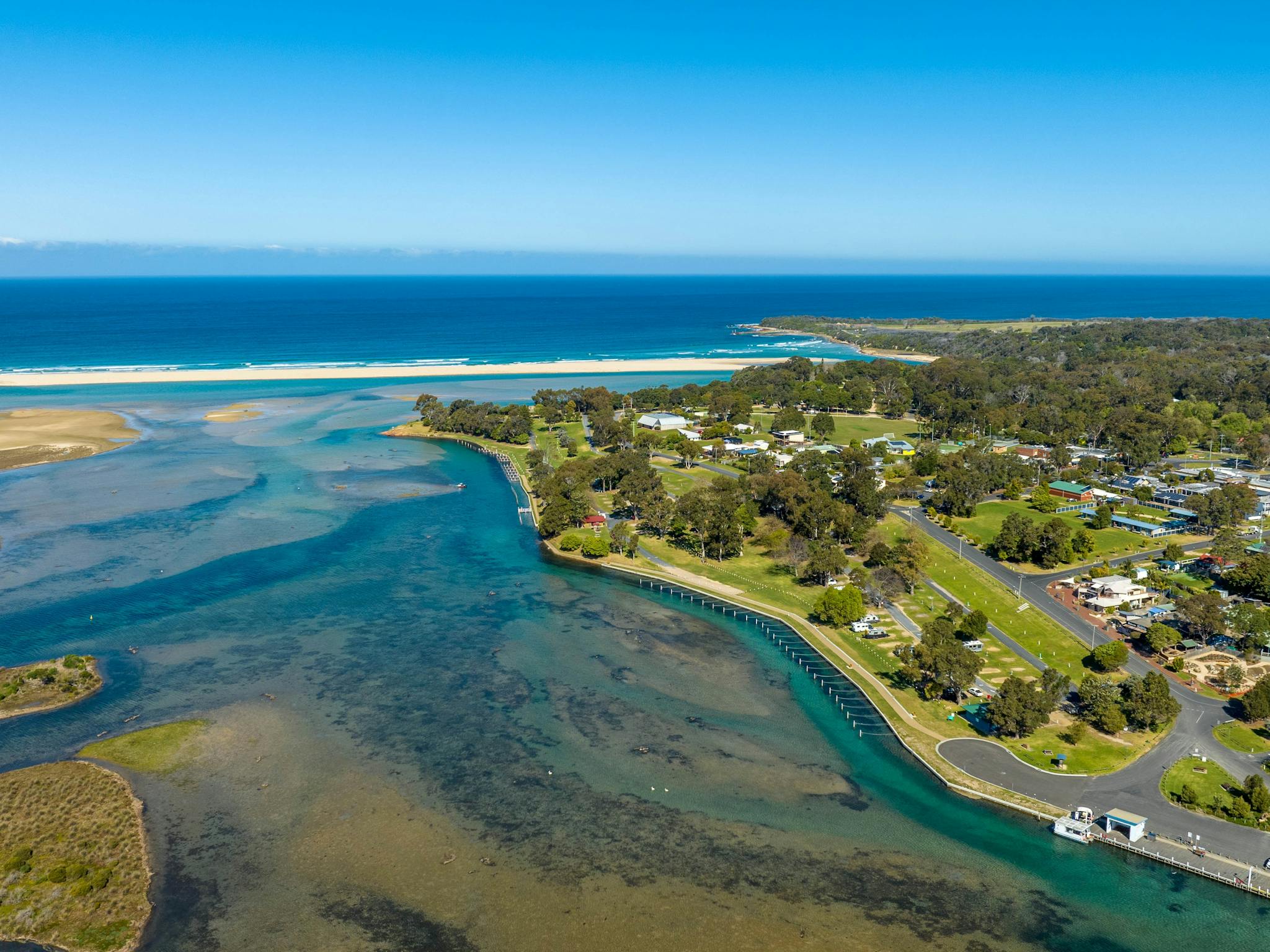 Aerial view of a Mallacoota Holiday Park, surrounded by lush greenery and water views