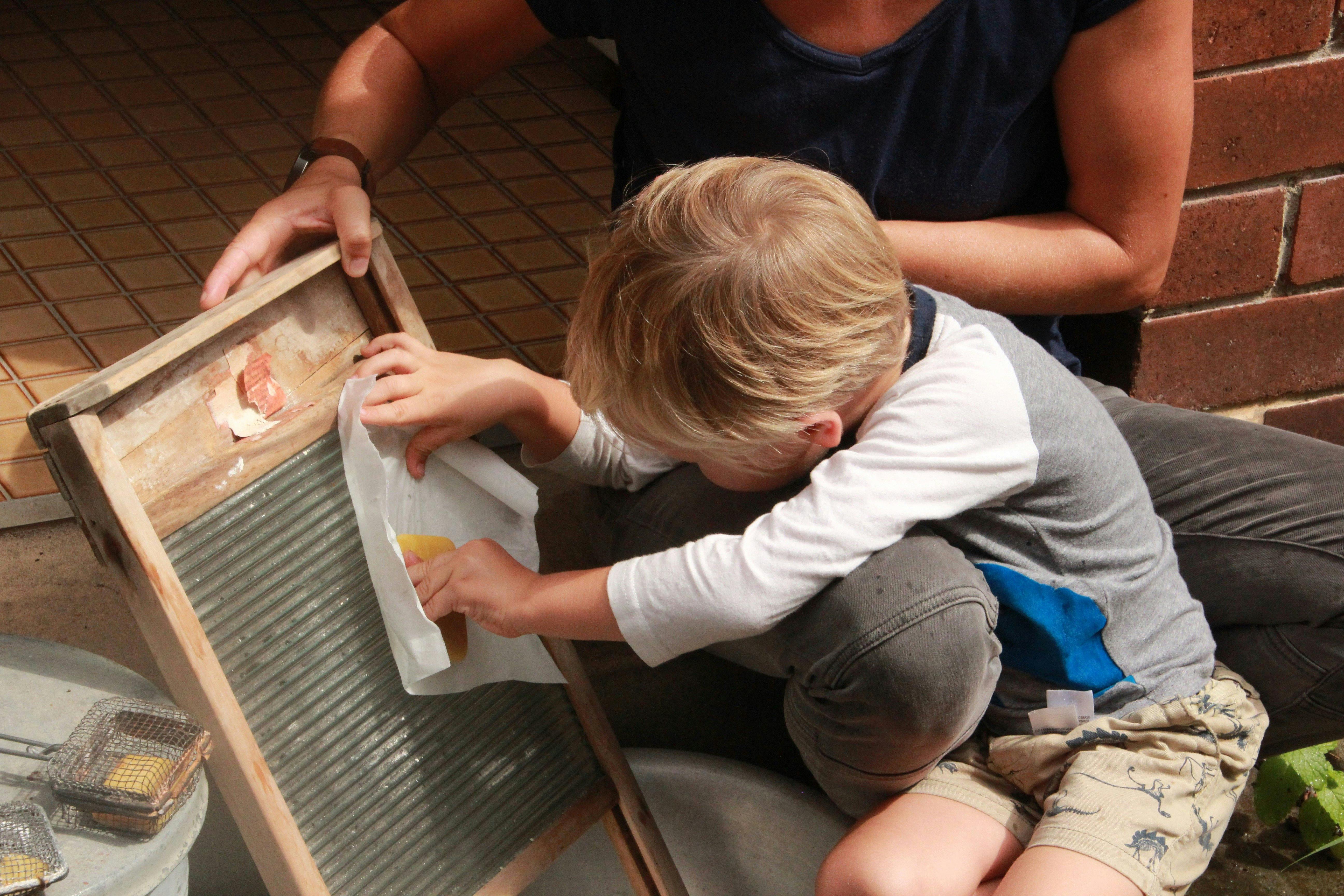 Young visitor uses washboard and soap to discover how to do the washing before washing machines
