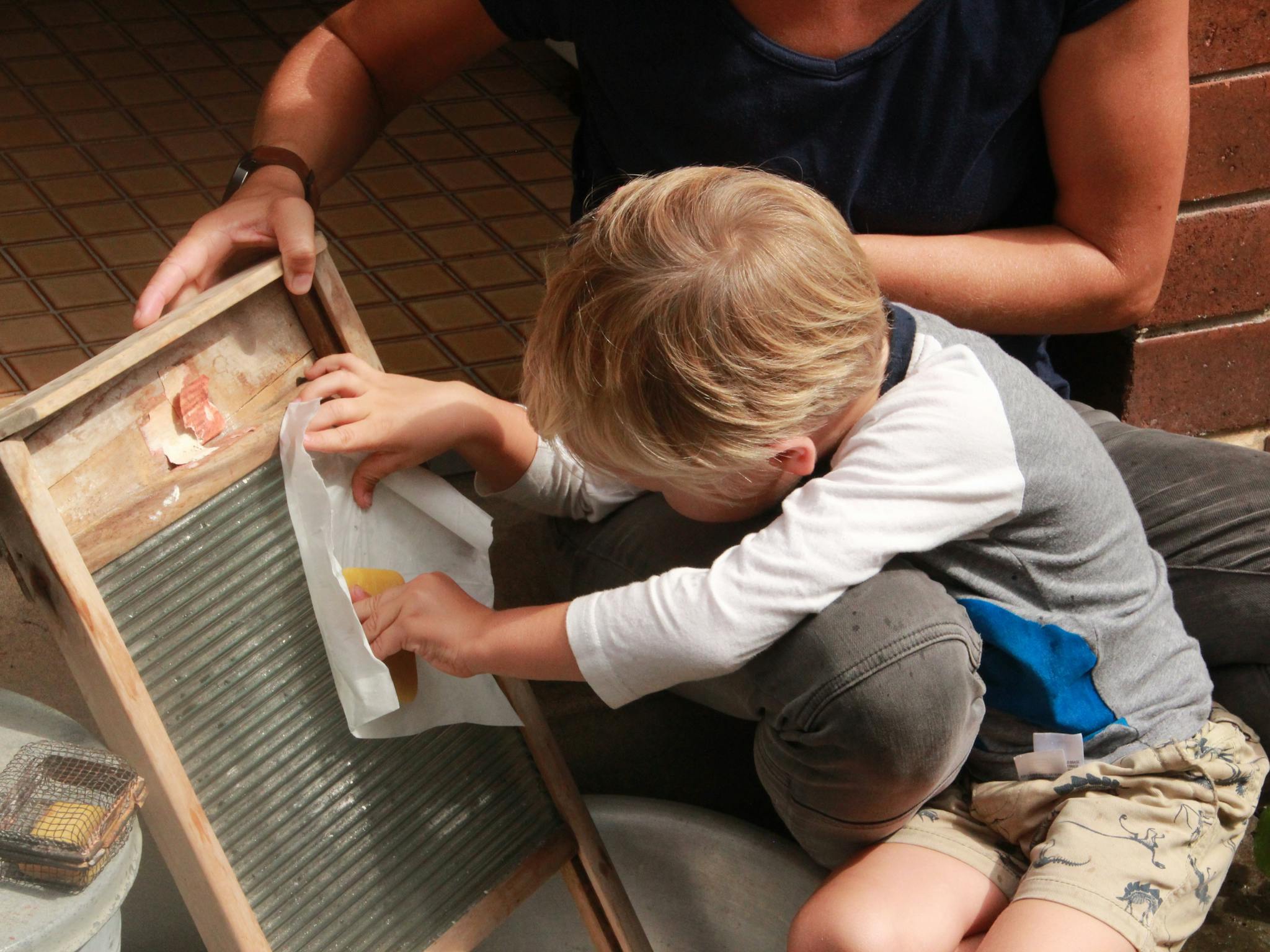 Young visitor uses washboard and soap to discover how to do the washing before washing machines