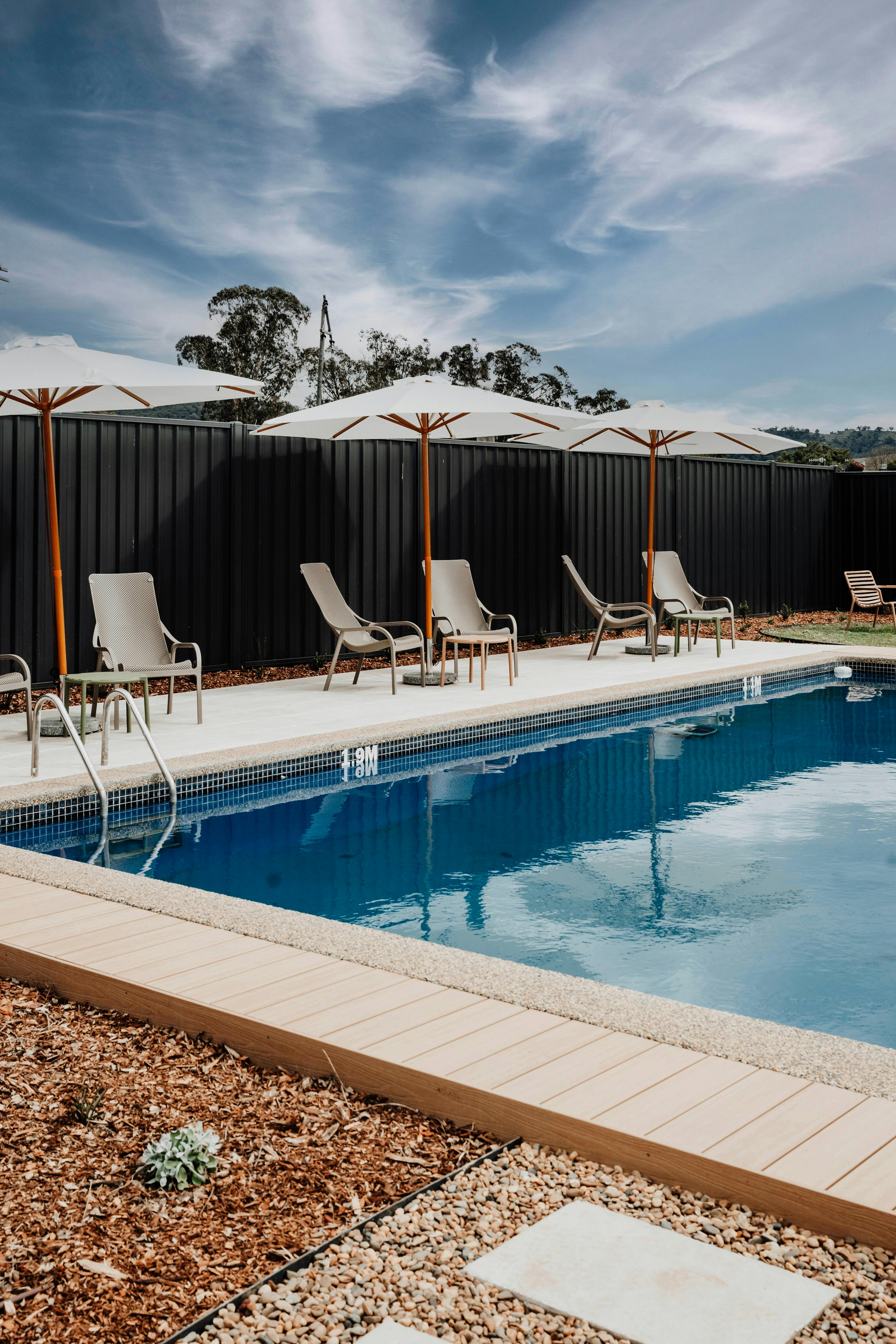 swimming pool with sun loungers and umbrellas under blue sky