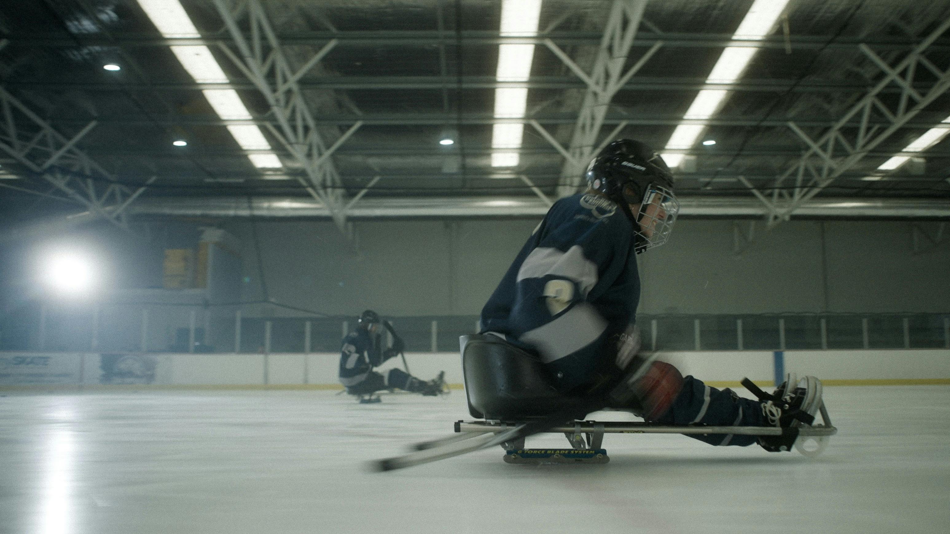 a person in full hockey gear races across the ice in their para-sled