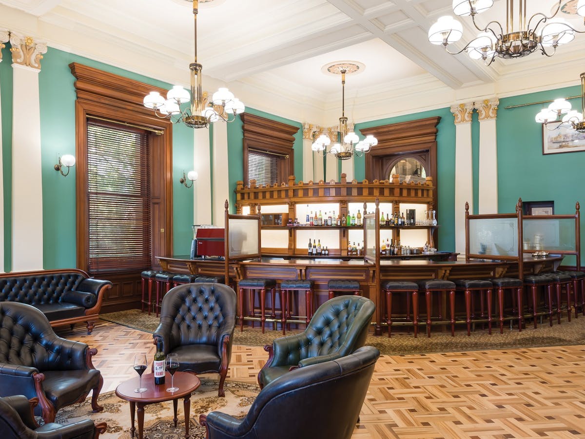 Ornate bar area with leather seating, wood accents, and ambient lighting. Ornate bar area with leather seating, wood accents, and ambient lighting.
