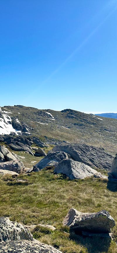 Large boulders in the mountains with some snow on a peak behind it.