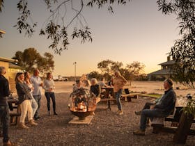A group of patrons are socialising in the hotel's outdoor area at twilight.