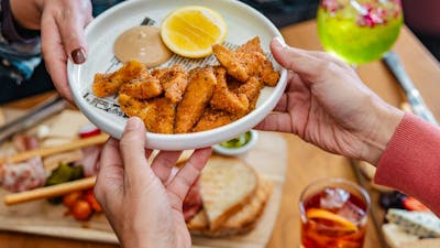 Hand passing plate of salt & pepper squid