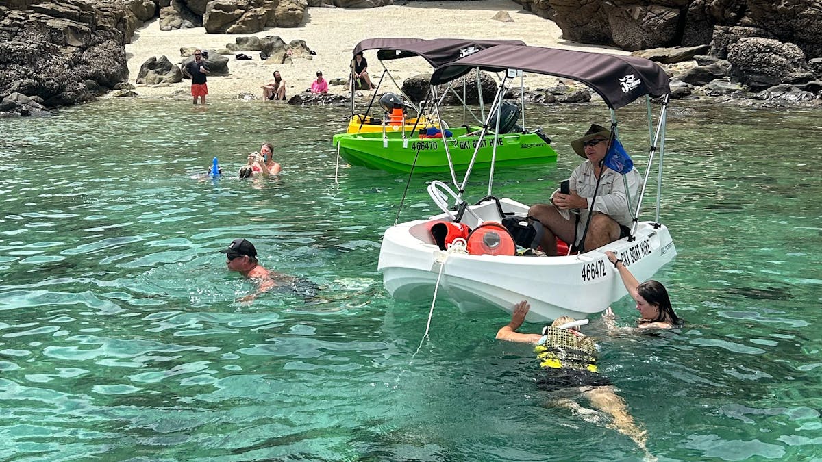 Snorkelling beside hire boats in clear water at Great Keppel Island, QLD.