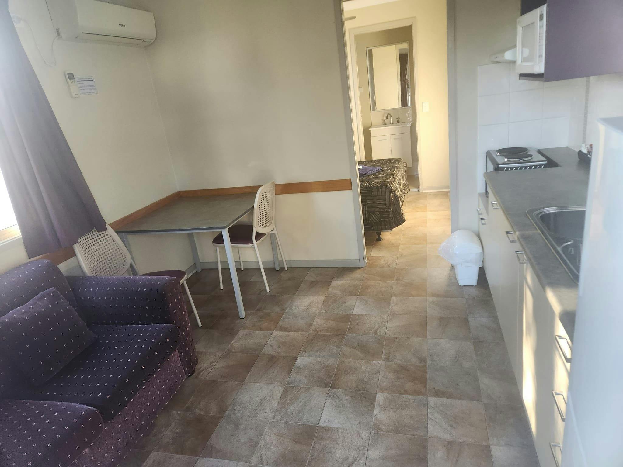 Interior of cabin Lounge square two seater table & kitchen  room at front Bed & ensuite in back room