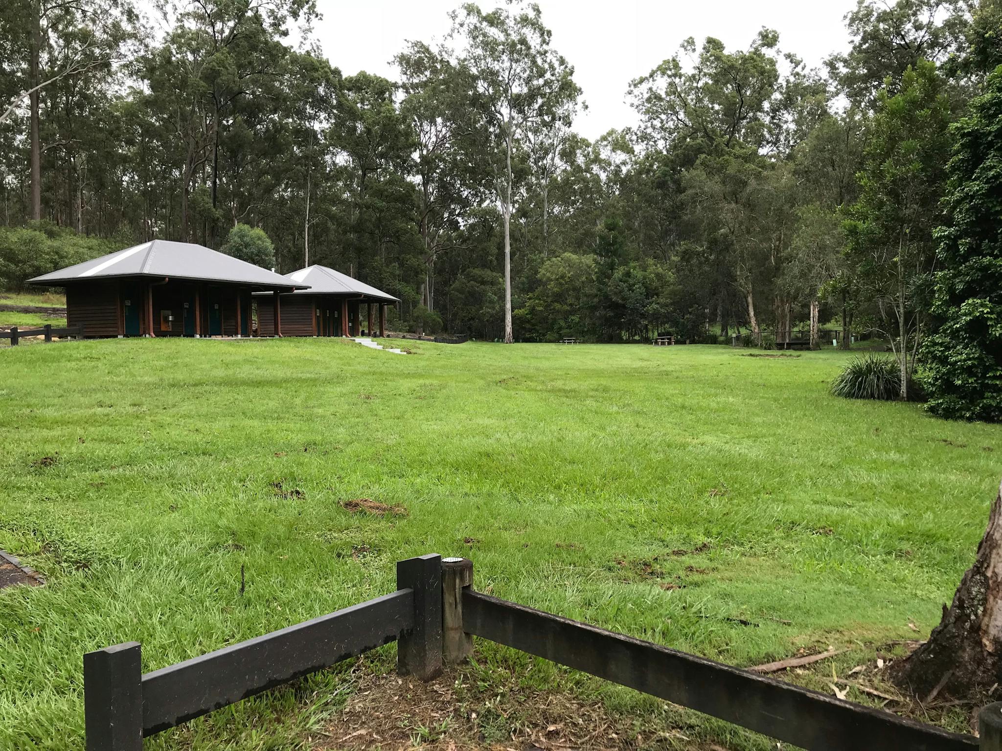 Shelter shed sits in grassy open space fringed by forest. Shelter shed sits in grassy open space fringed by forest.