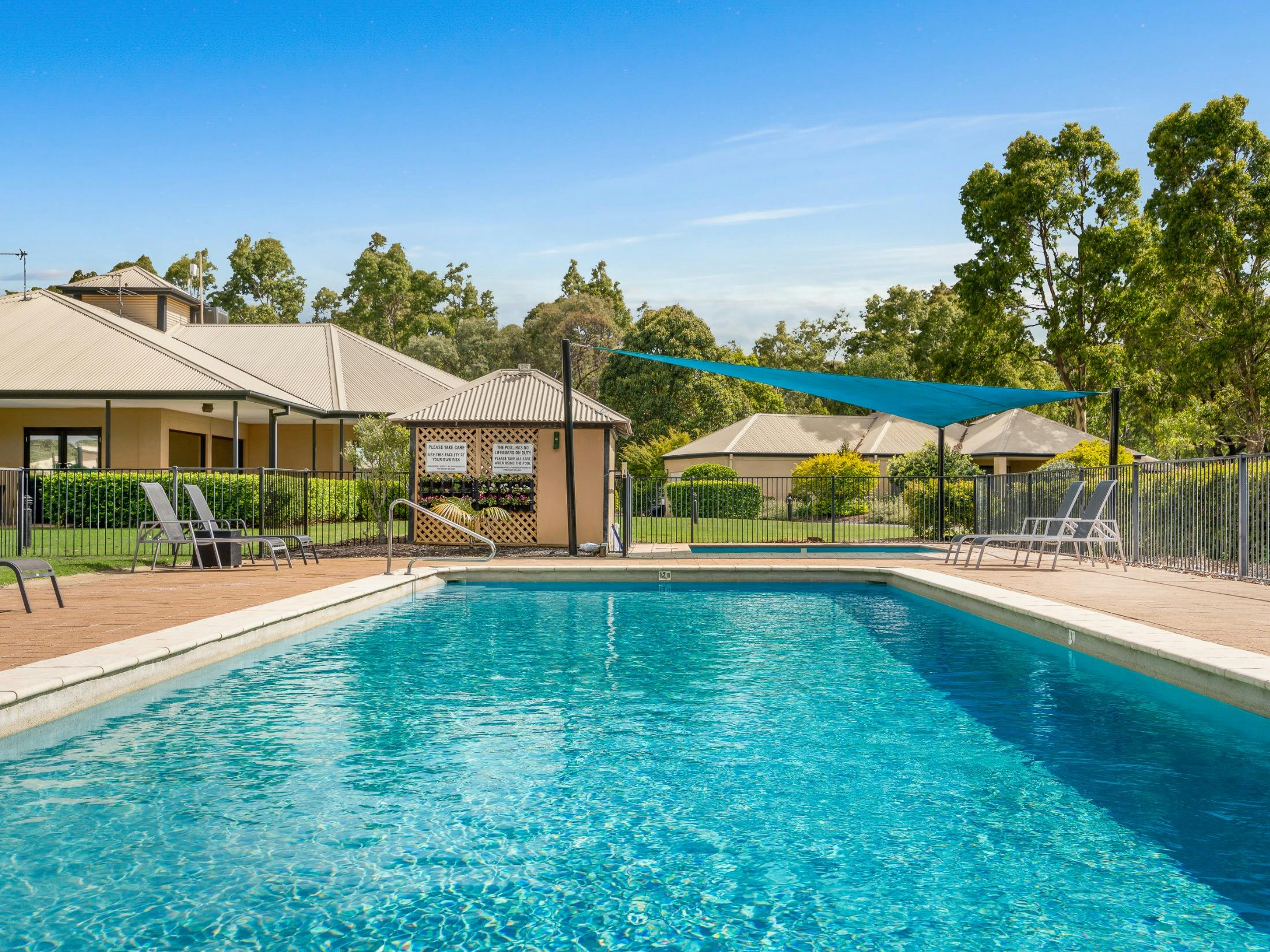 Resort swimming pool with shade sails and surrounding villas